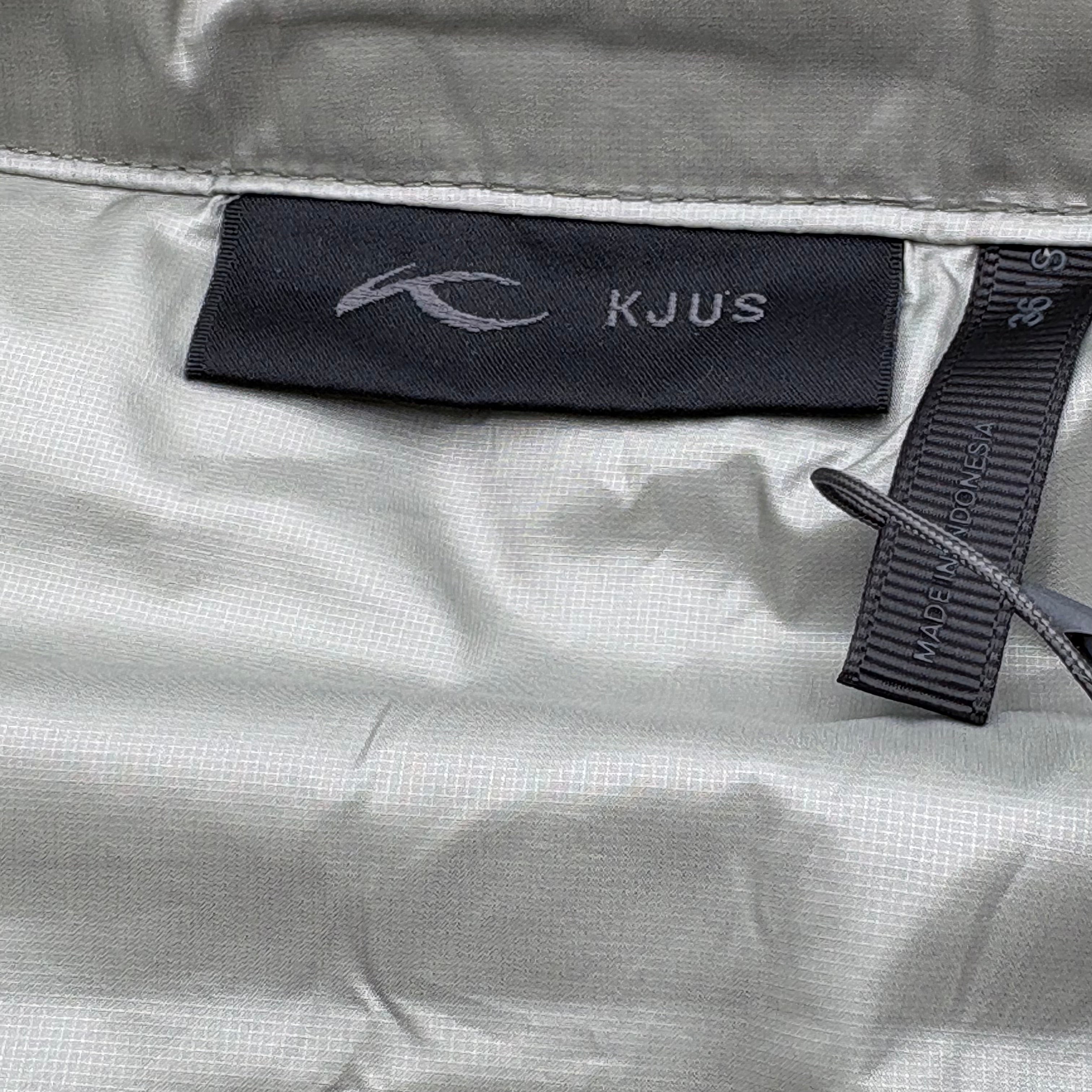 KJUS label on a gray fabric surface