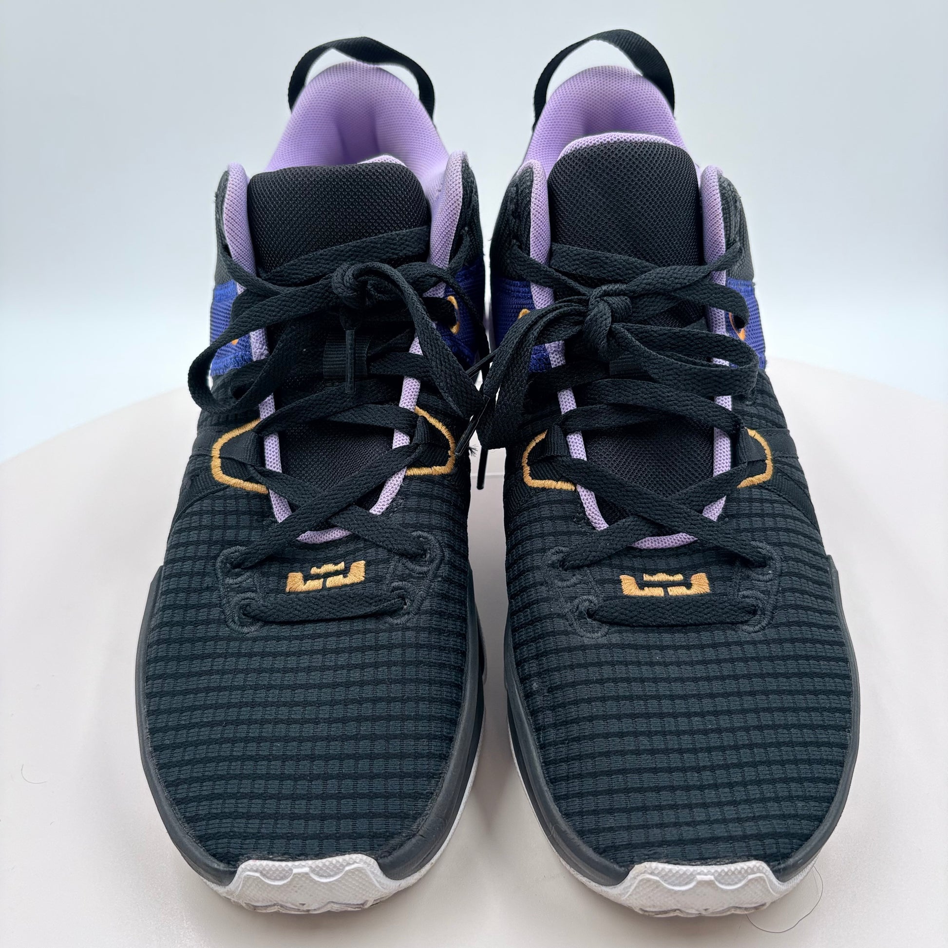 Pair of dark gray athletic shoes with purple accents on a white background