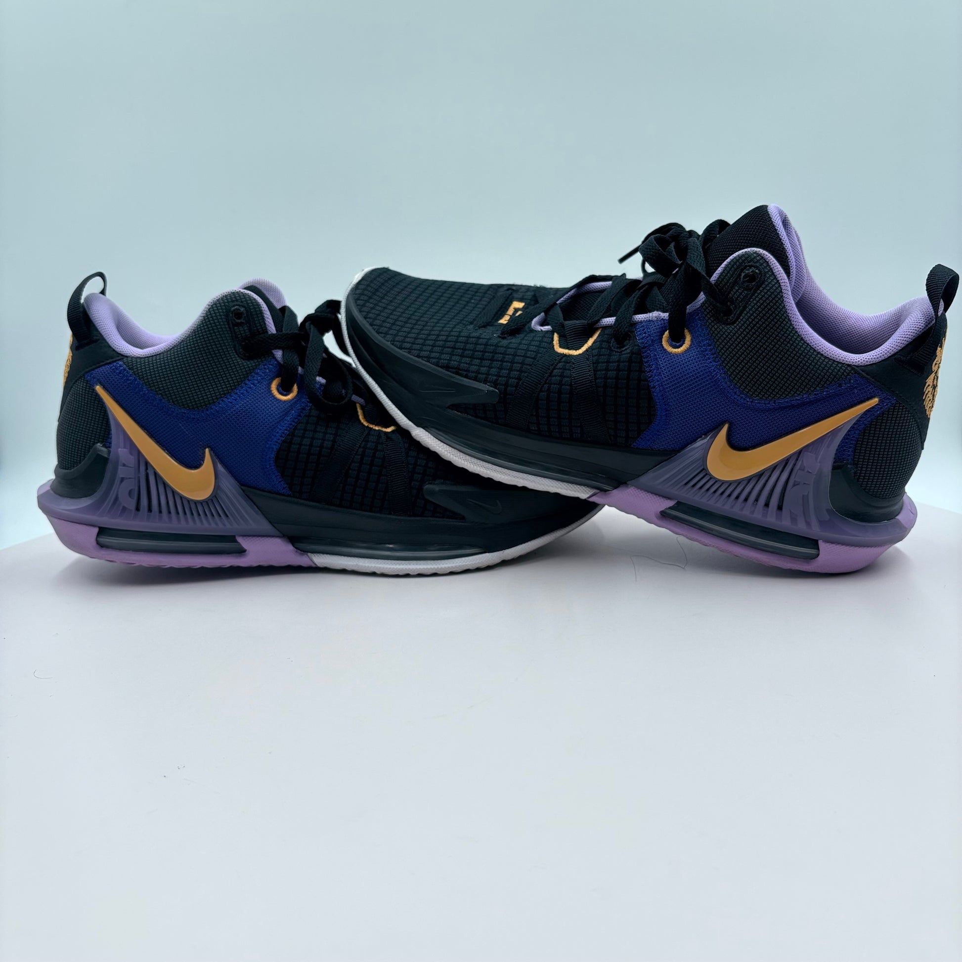 Pair of black and purple sneakers with gold accents on a light gray background