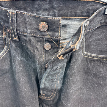 Close-up of dark blue denim jeans with buttons and stitching details.