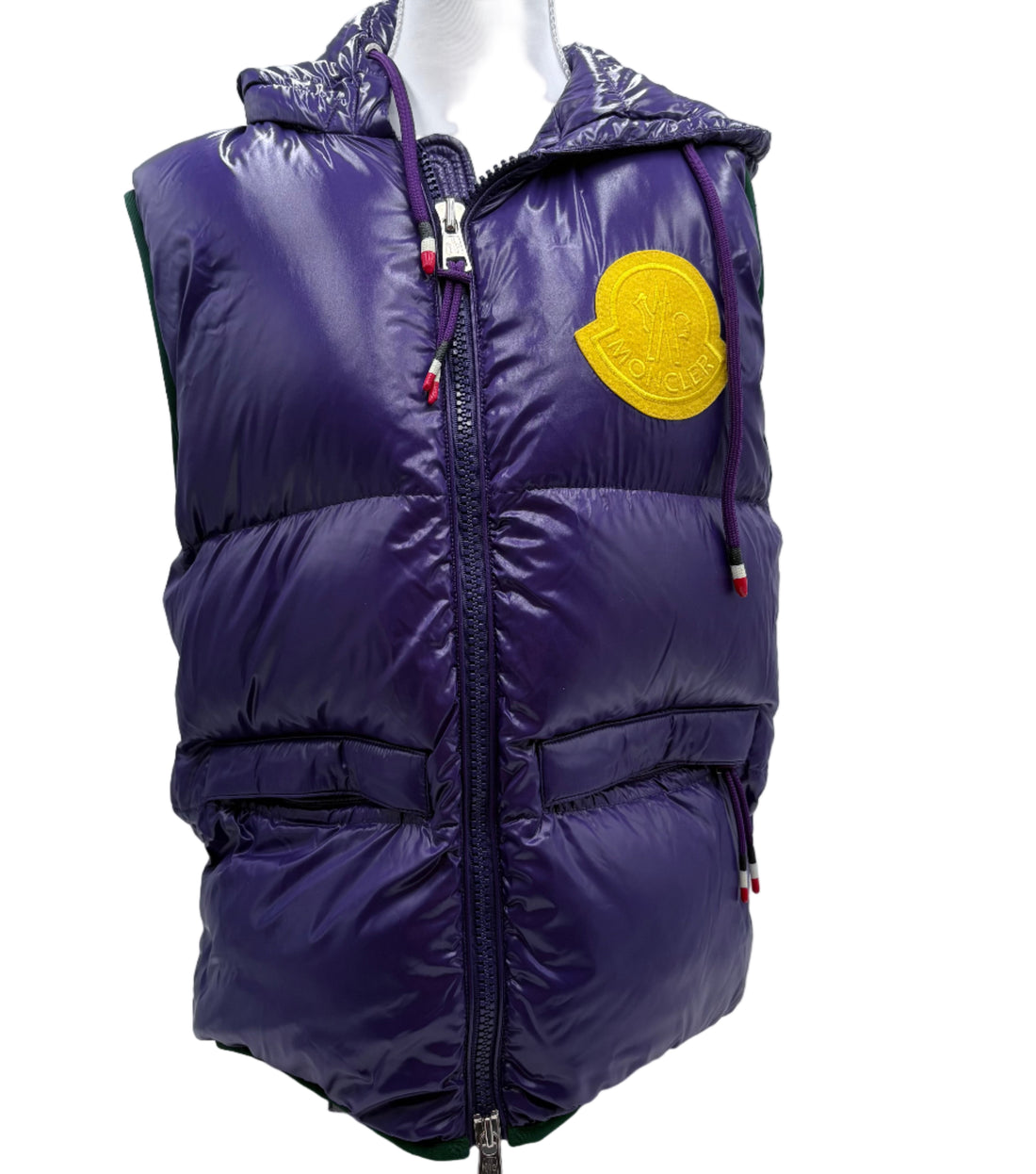 Purple puffer vest with a yellow patch on a mannequin, displayed against a white background.