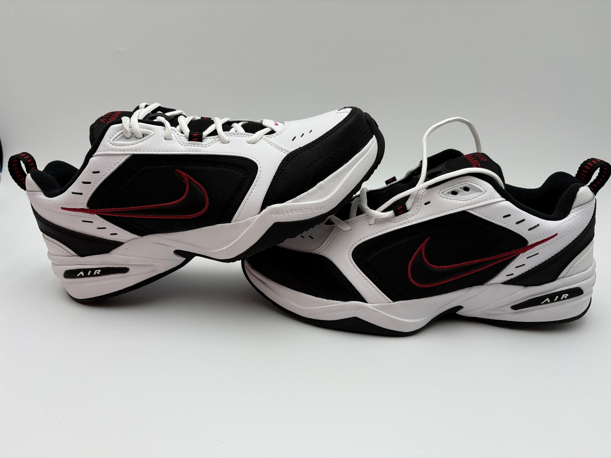 White and black Nike sneakers with red accents on a gray background