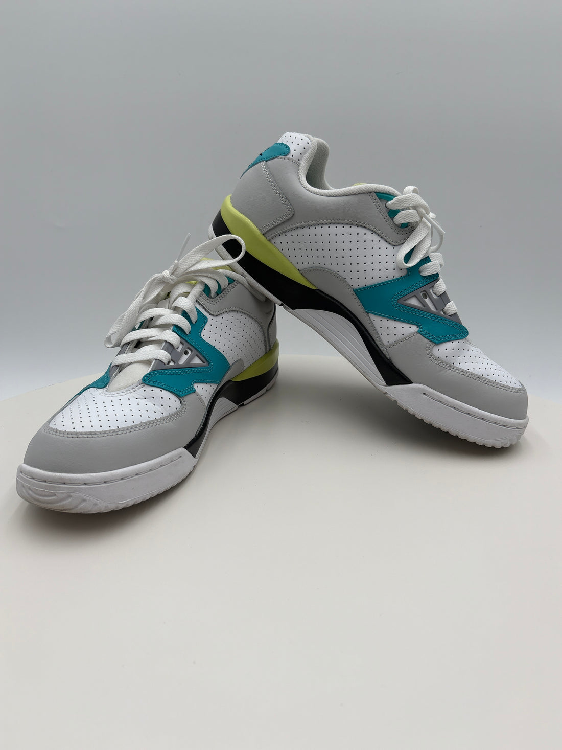 Pair of white sneakers with blue and green accents on a gray background