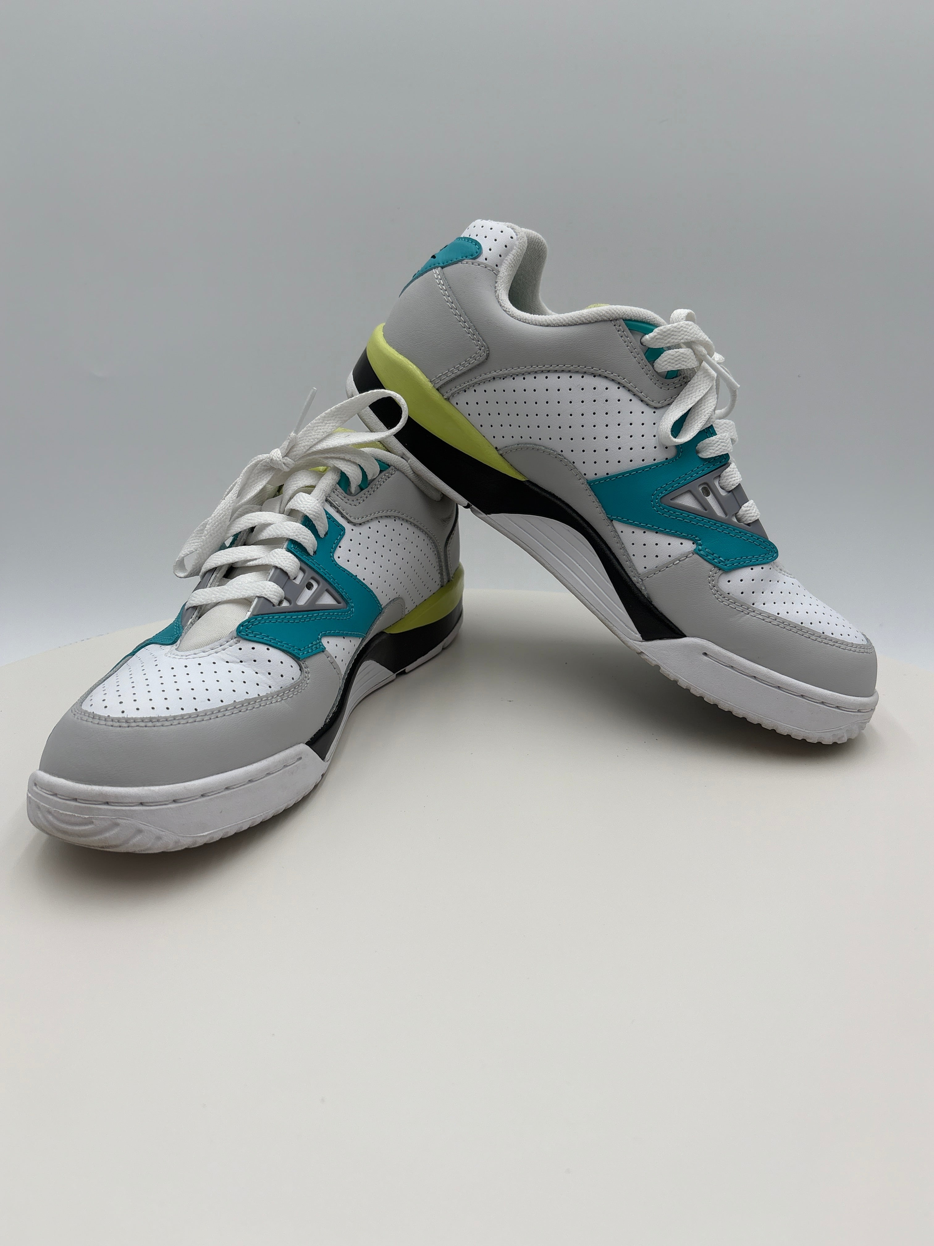 Pair of white sneakers with blue and green accents on a gray background