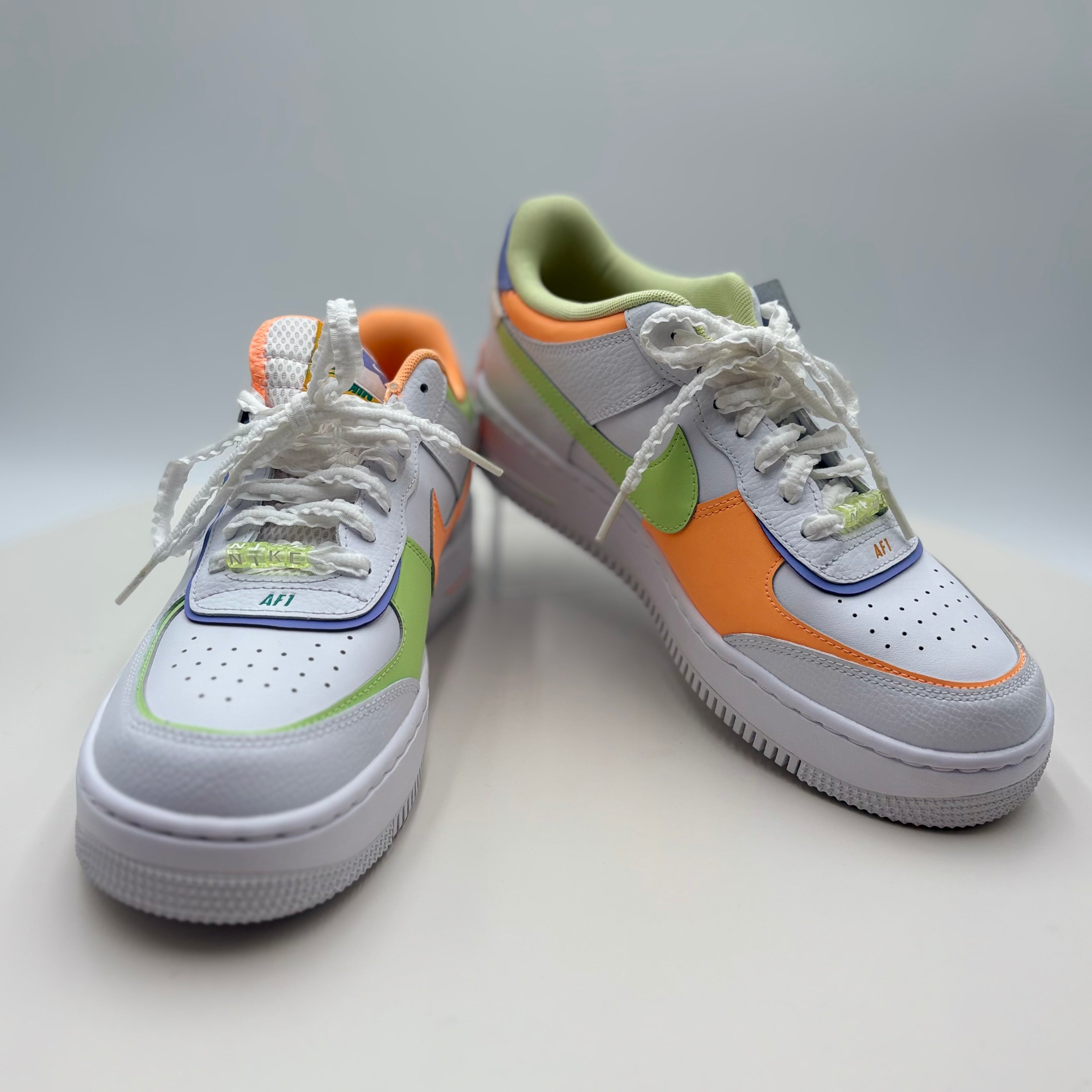 White sneakers with orange and green accents on a light gray background