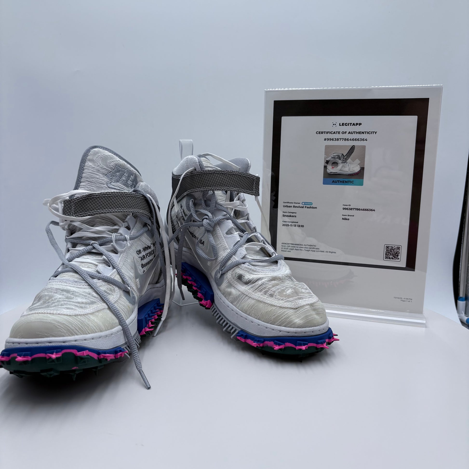 Pair of white sneakers with colorful soles next to a certificate of authenticity on a white background