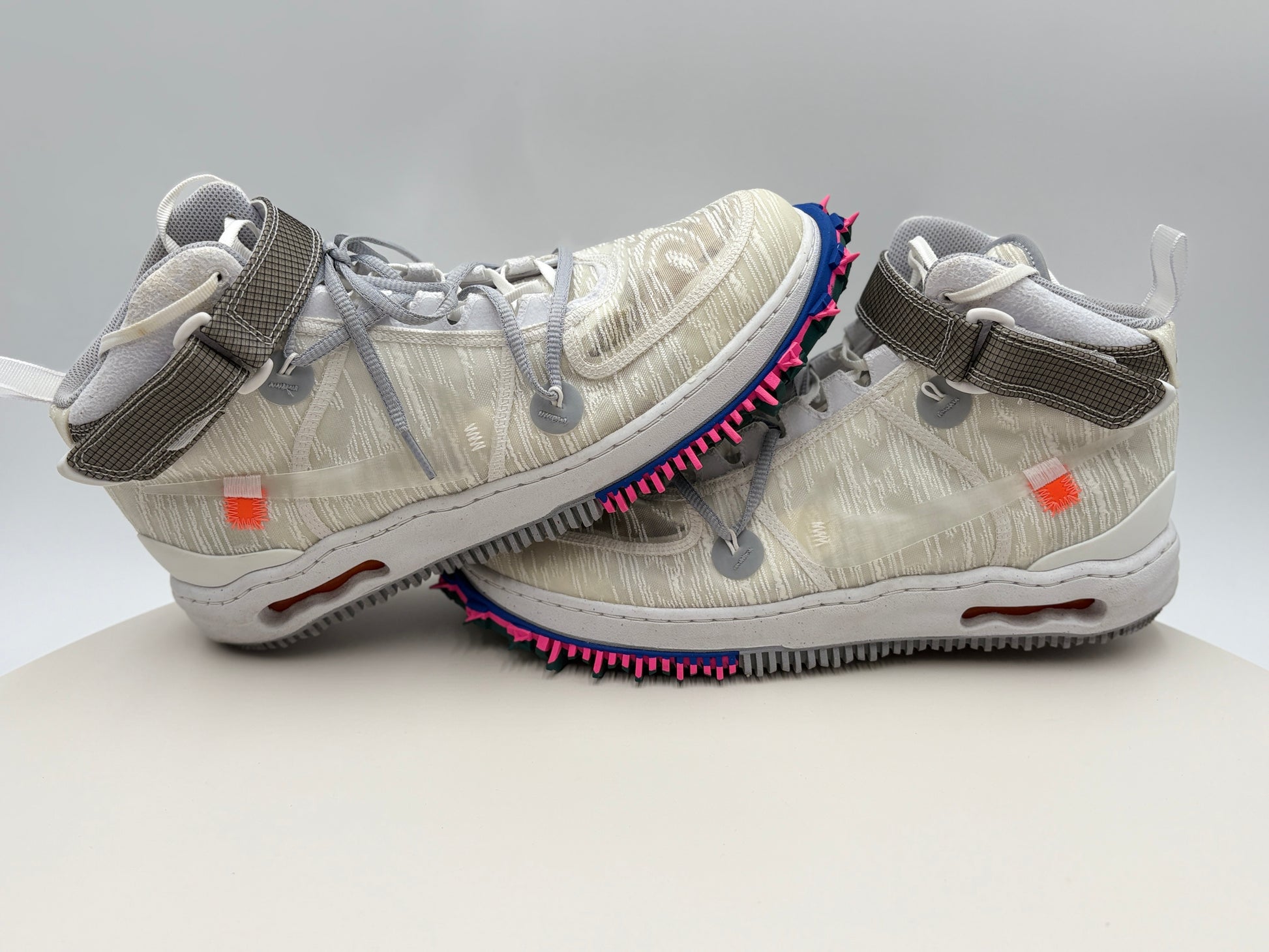 Pair of white sneakers with unique design elements on a light gray background