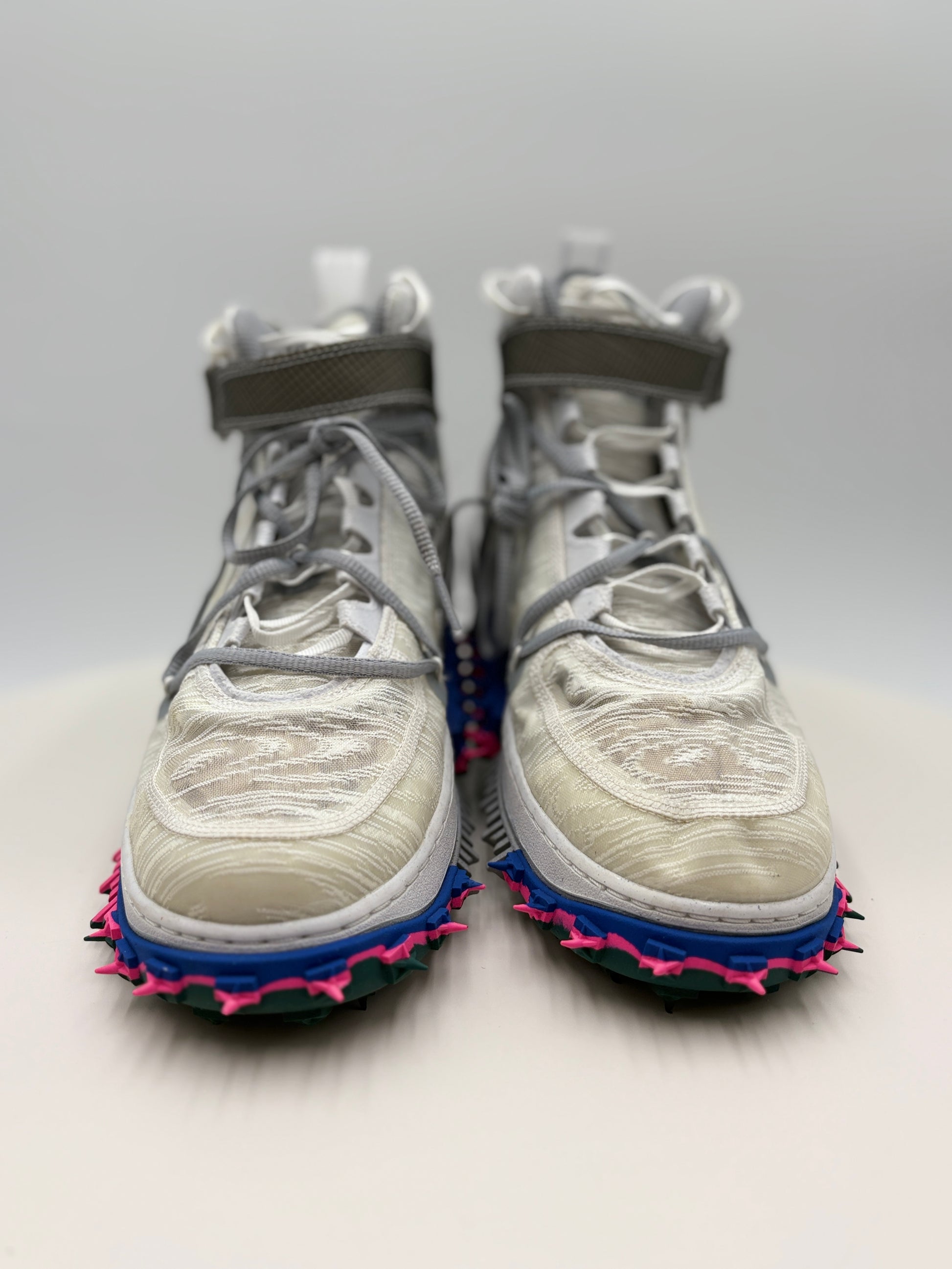 Pair of high-top sneakers with unique sole designs on a light gray background