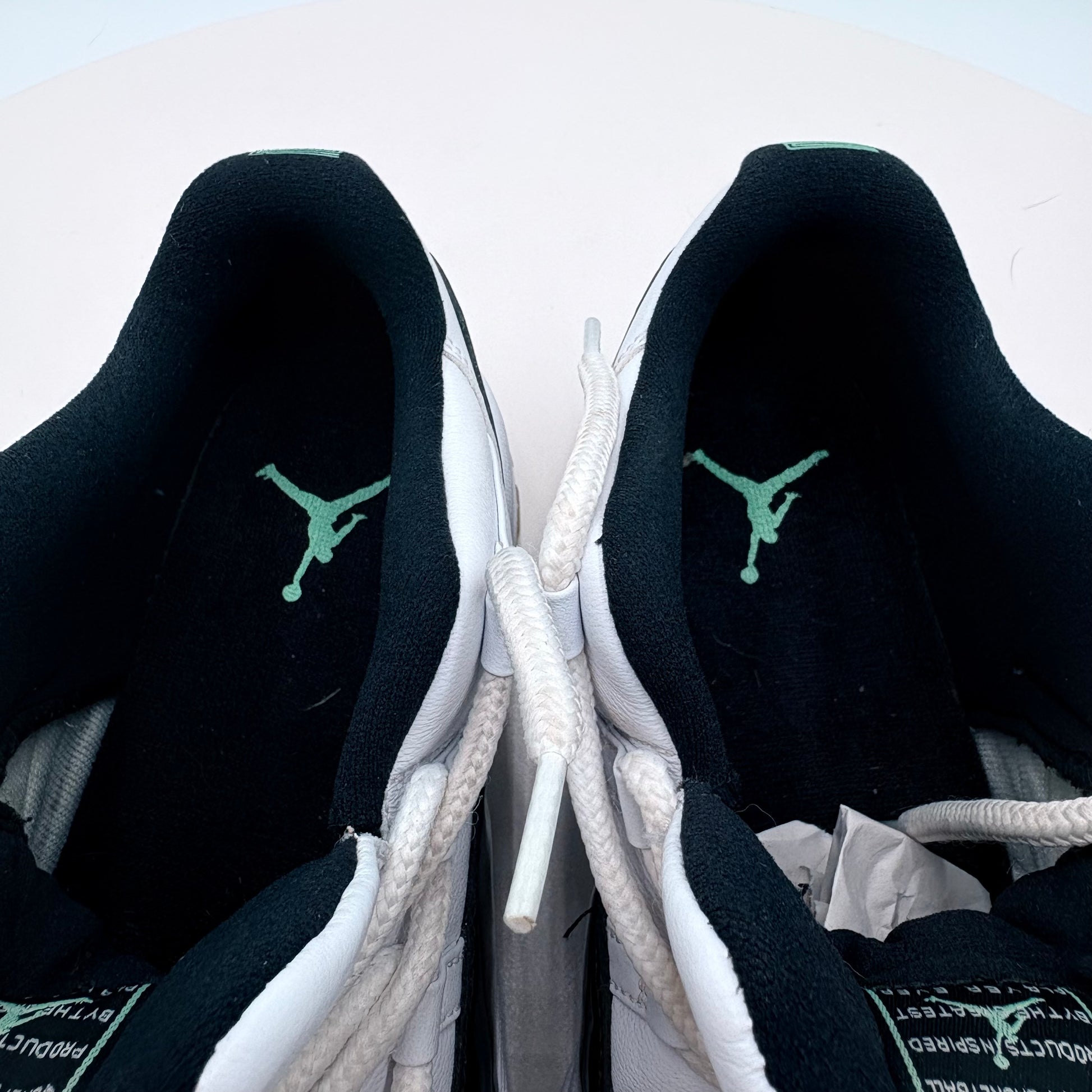 Black and white sneakers with green logo on a light gray background