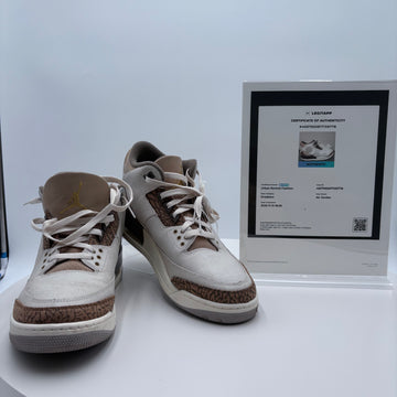 Pair of white and brown sneakers with a certificate on a white surface
