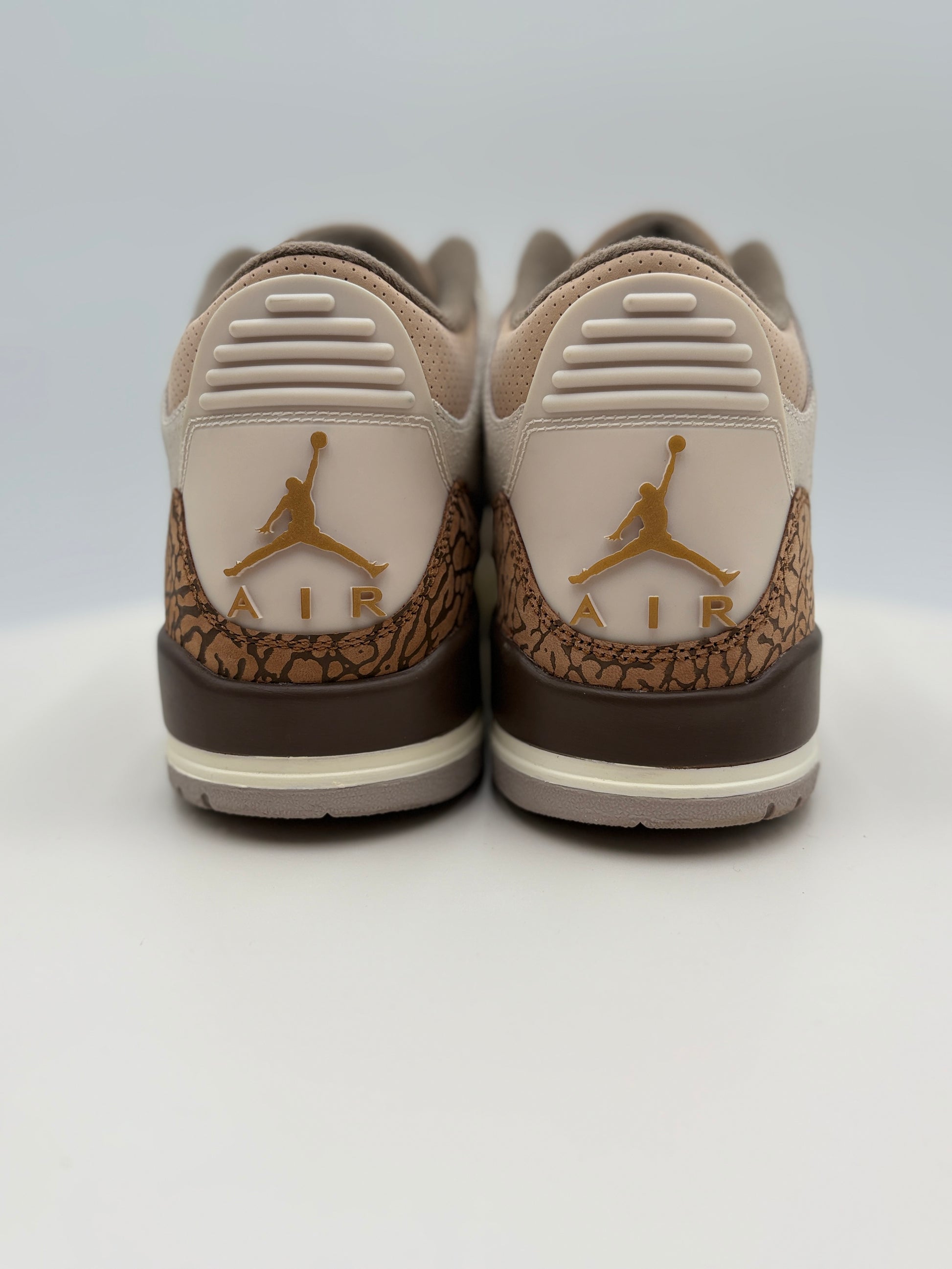 Pair of beige and brown sneakers with a logo on a white background