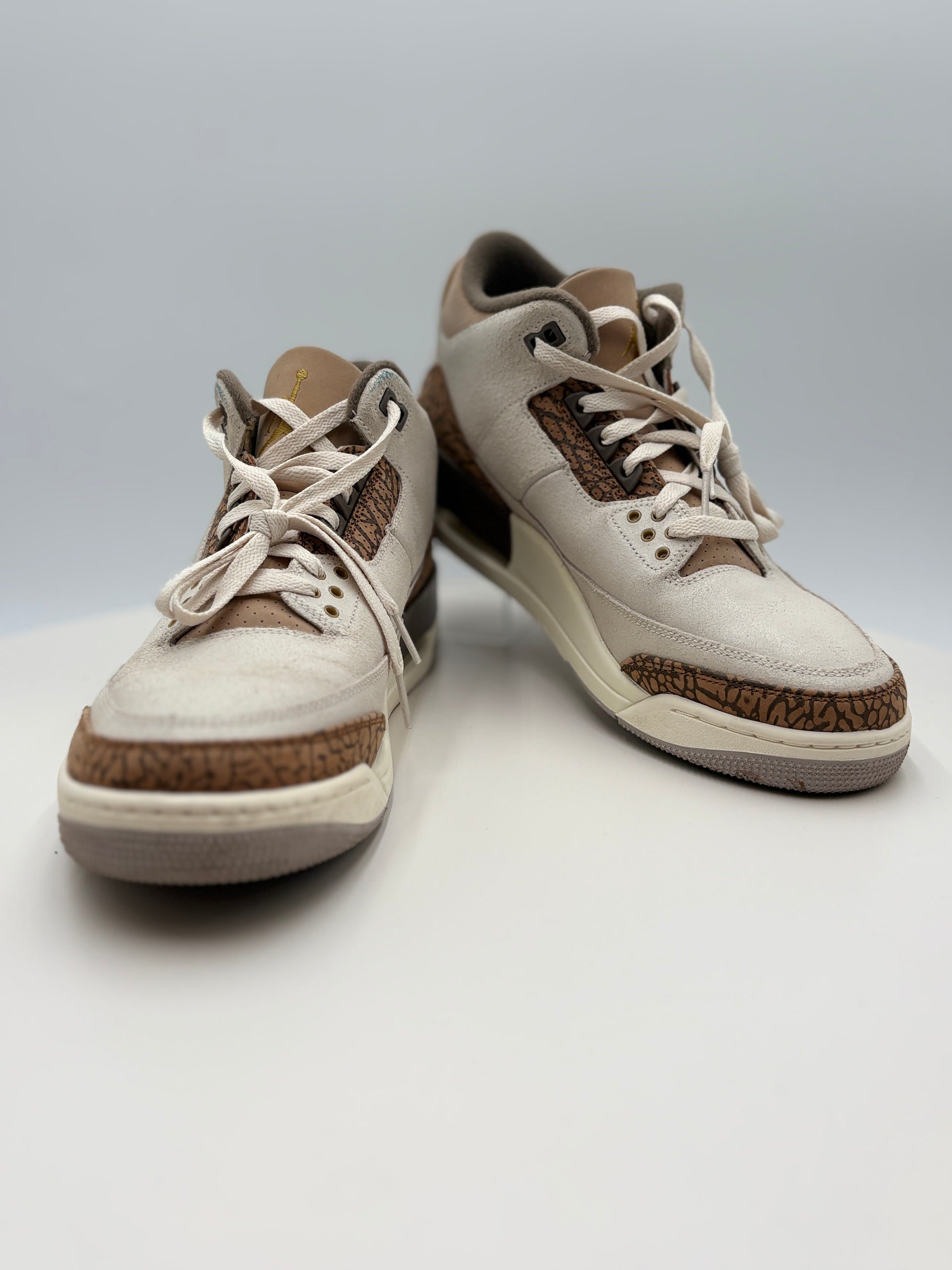 Pair of beige and brown sneakers on a light gray background