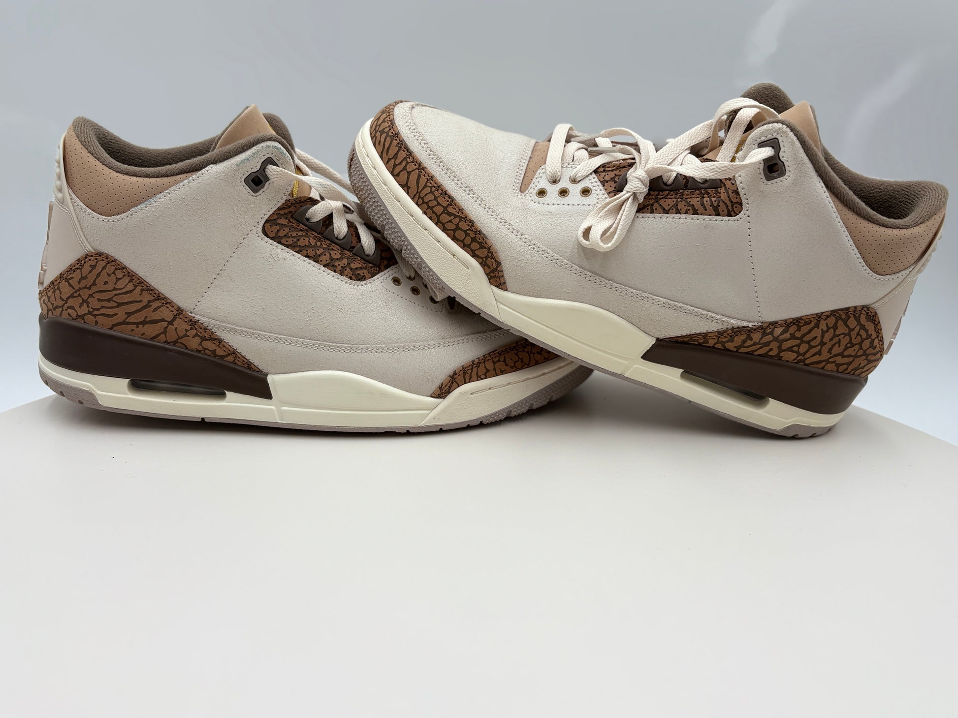 Pair of beige and brown sneakers on a light gray background