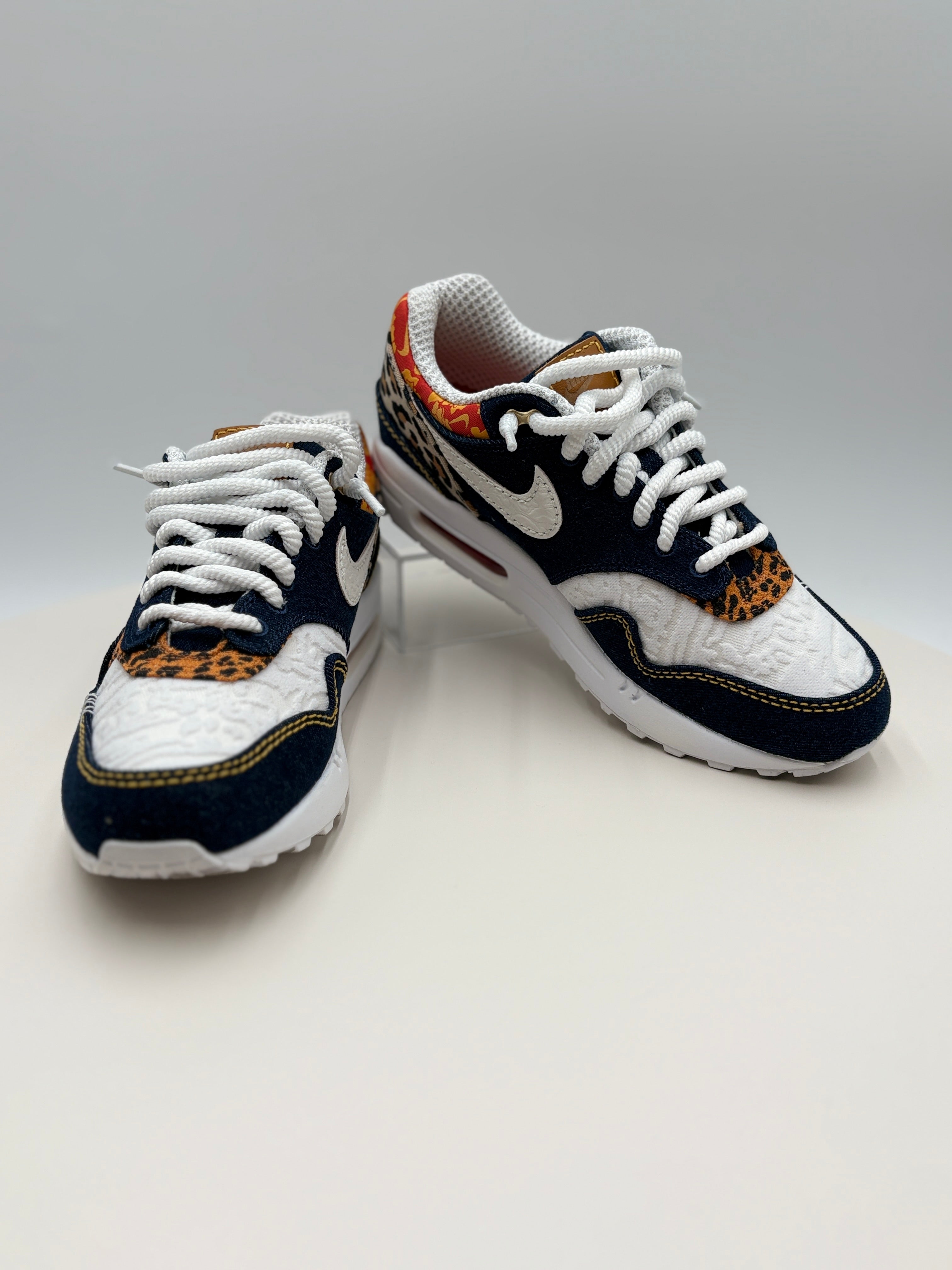 Pair of white and black sneakers with leopard print accents on a light gray background