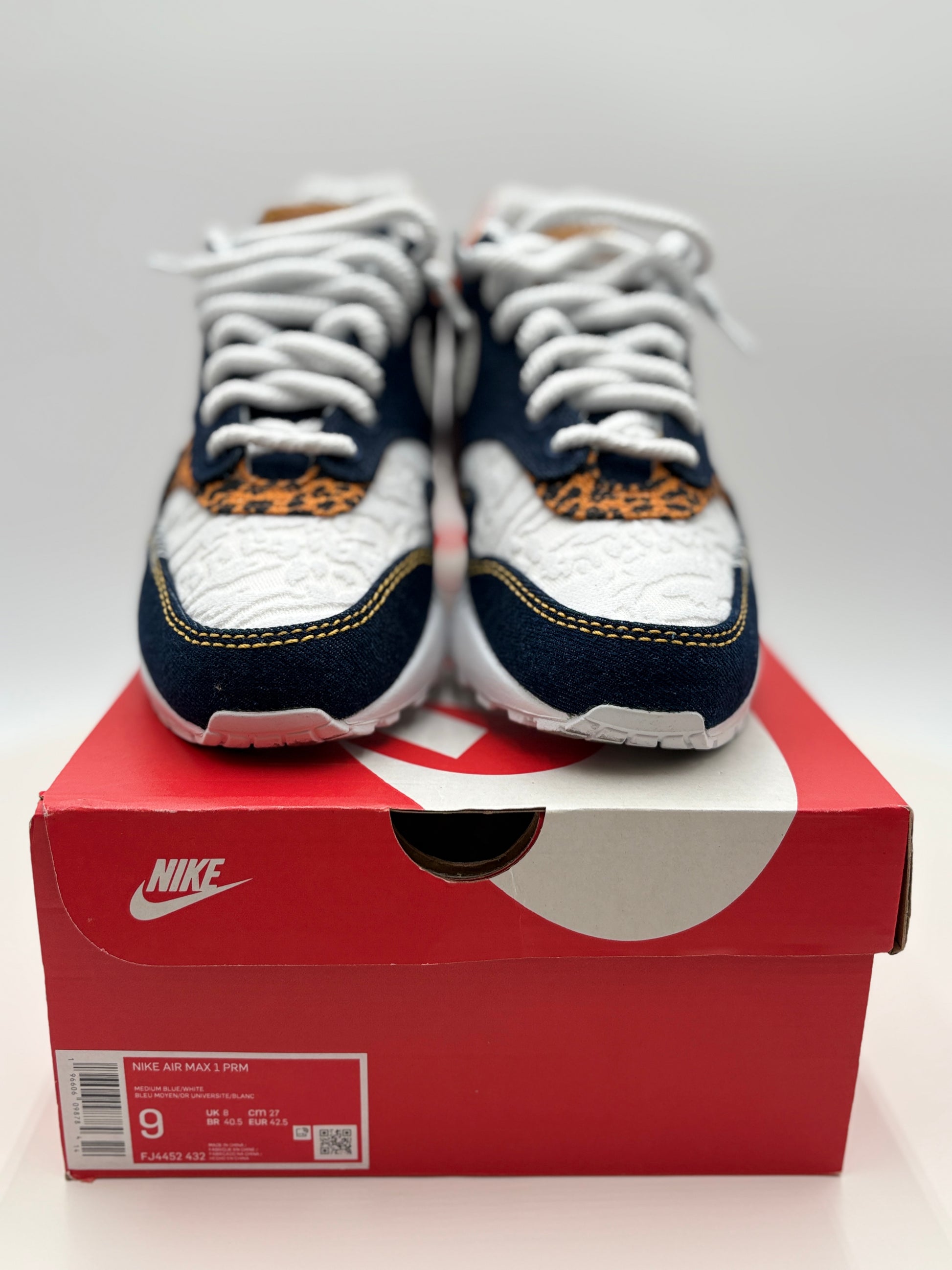 White and navy sneakers with orange accents on a red Nike box.