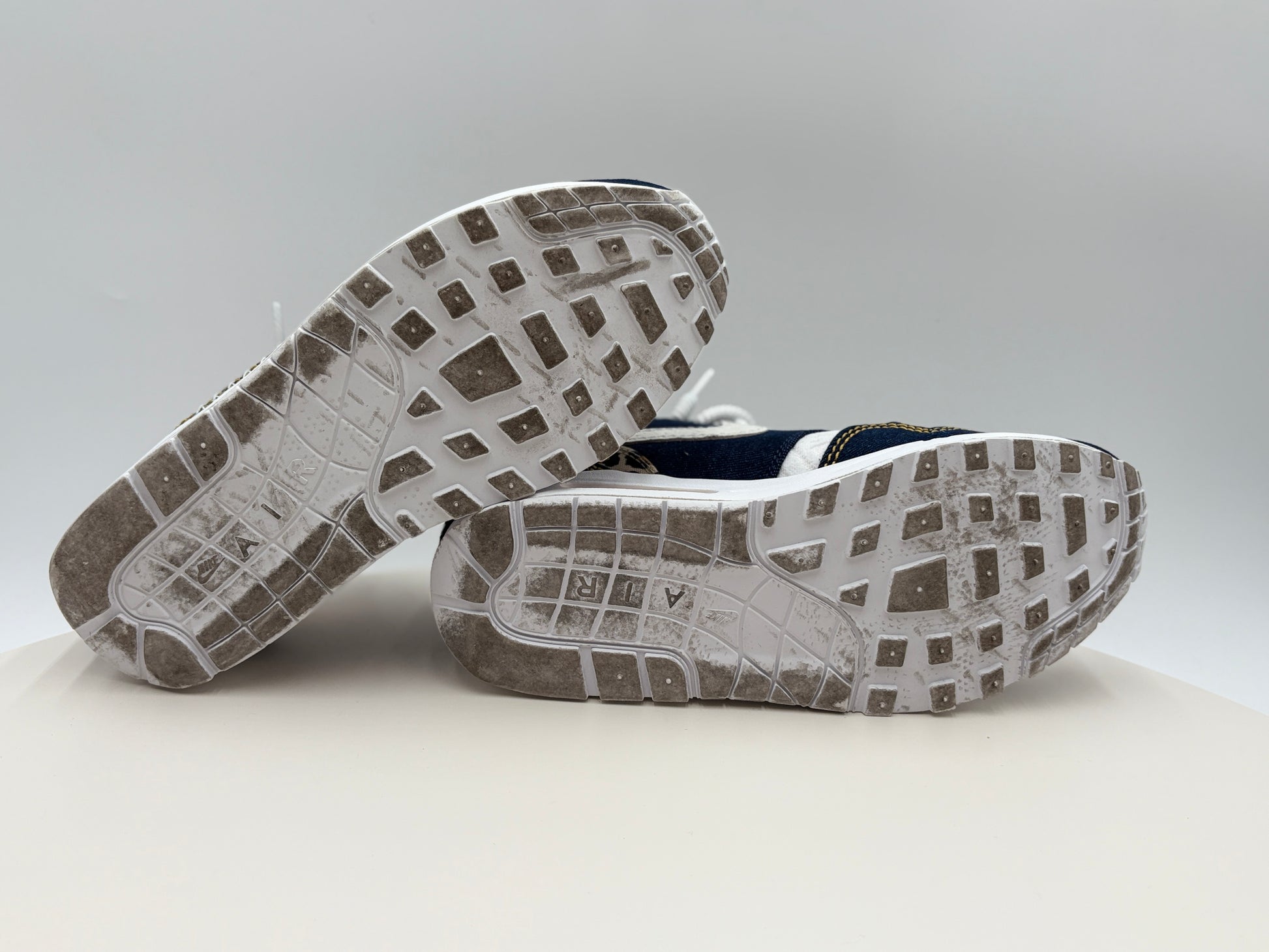 Close-up of a pair of shoes with soles facing upwards on a light gray background