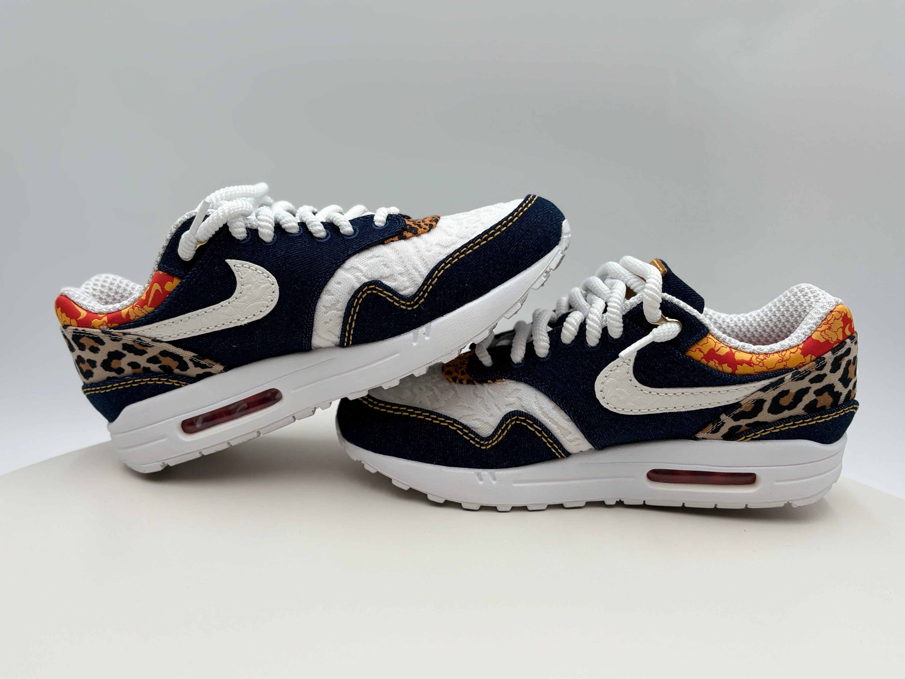 Pair of Nike sneakers with leopard print accents on a light gray background