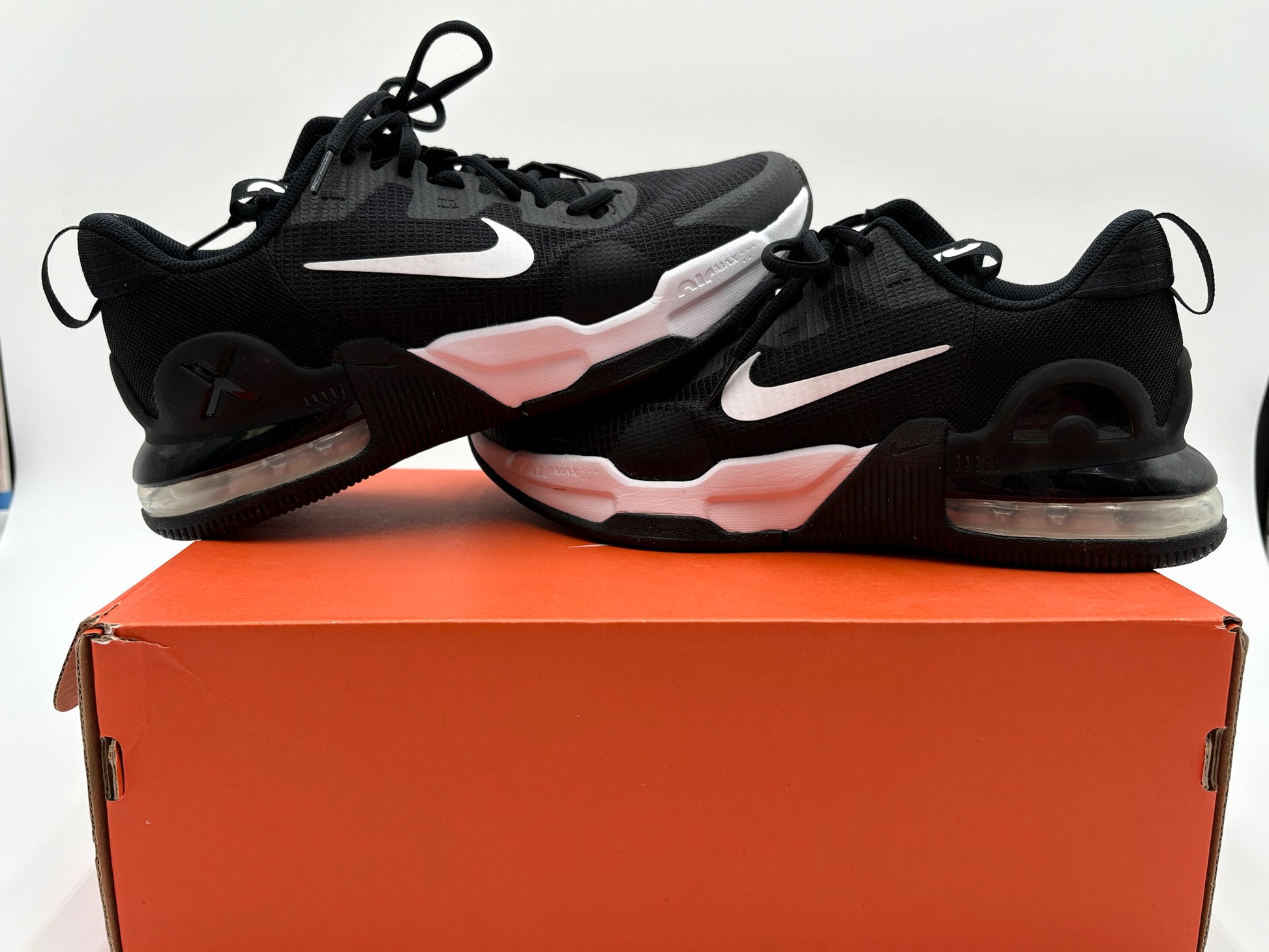 Black sneakers with white swoosh logo on an orange box against a white background