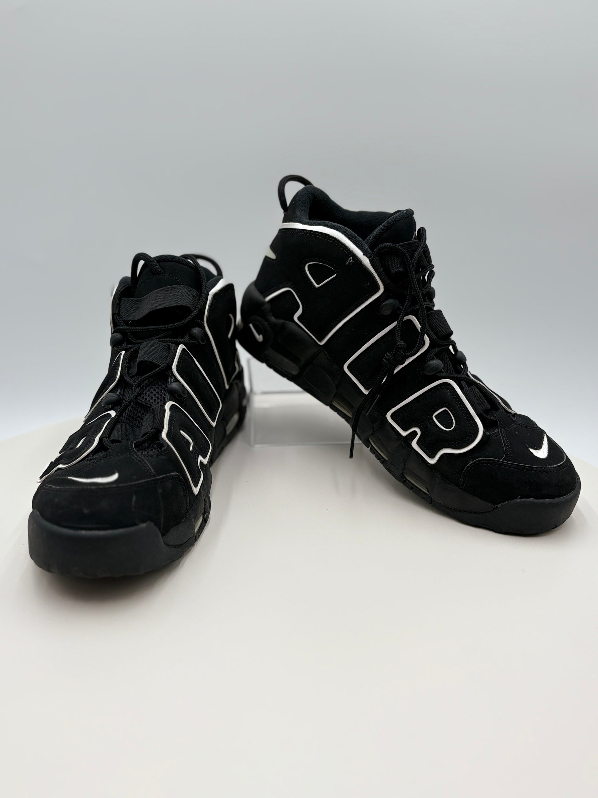 Black high-top sneakers with white accents on a light gray background