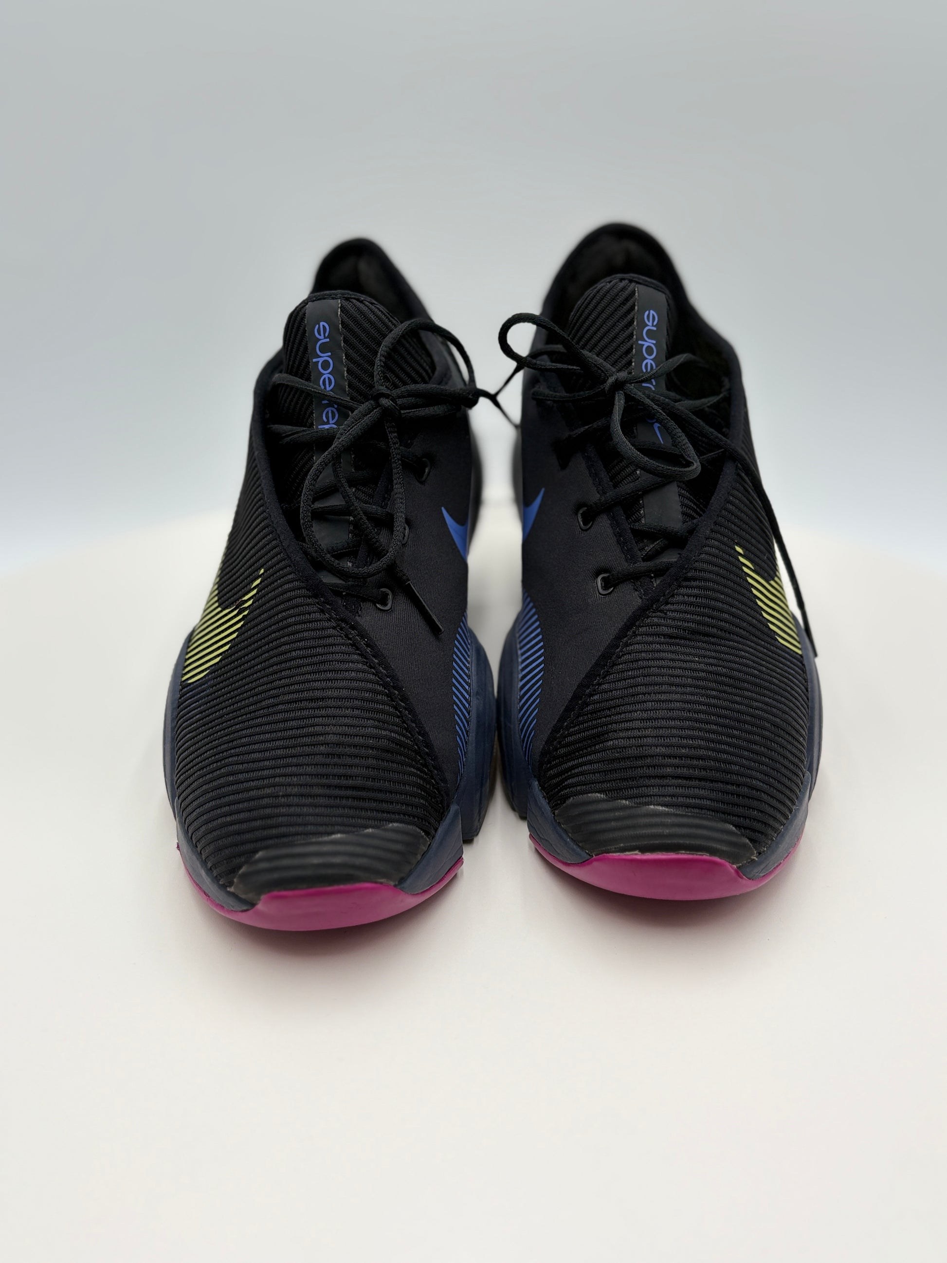 Black athletic shoes with pink soles on a white background