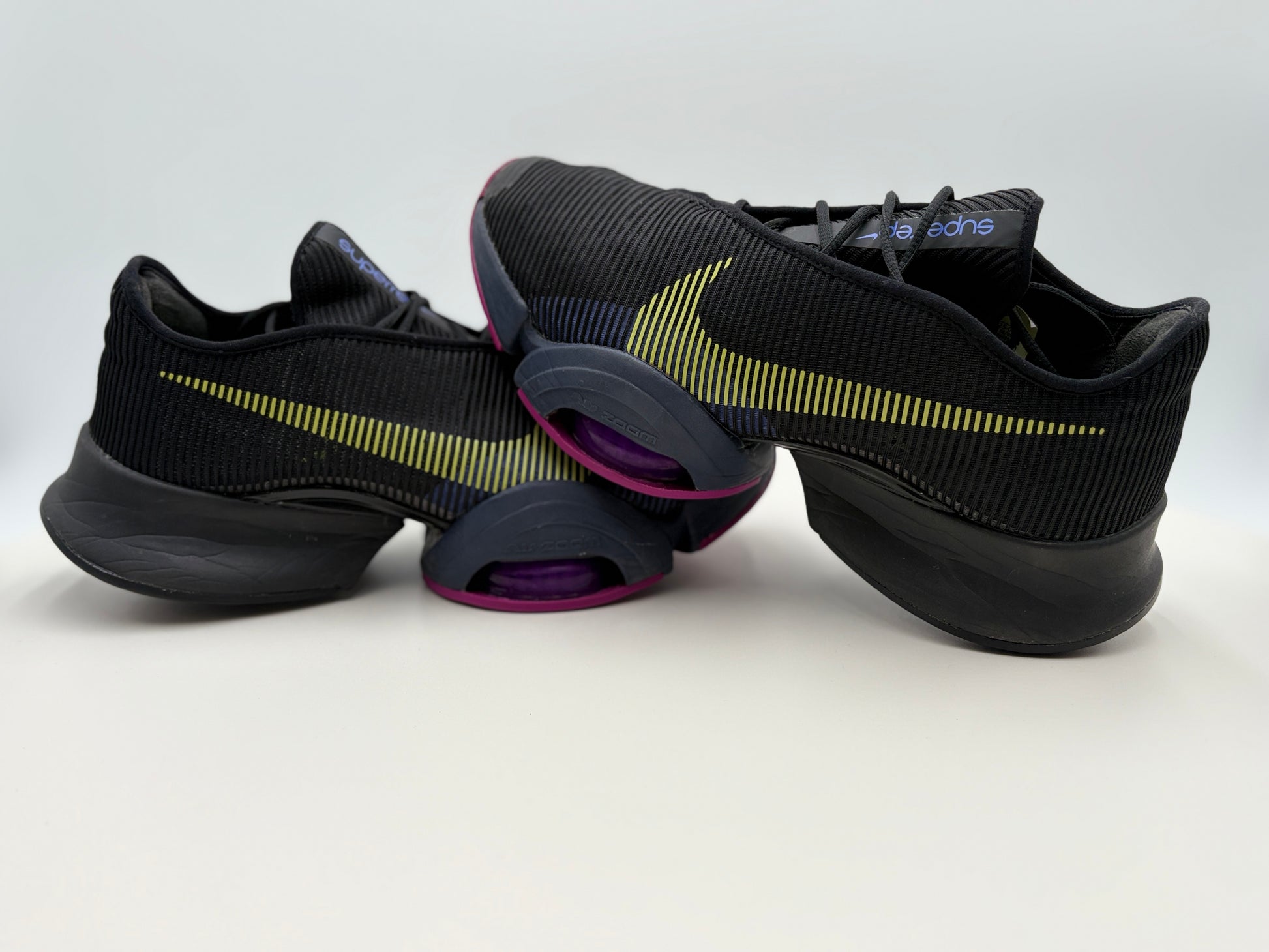 Black athletic shoes with yellow accents on a white background