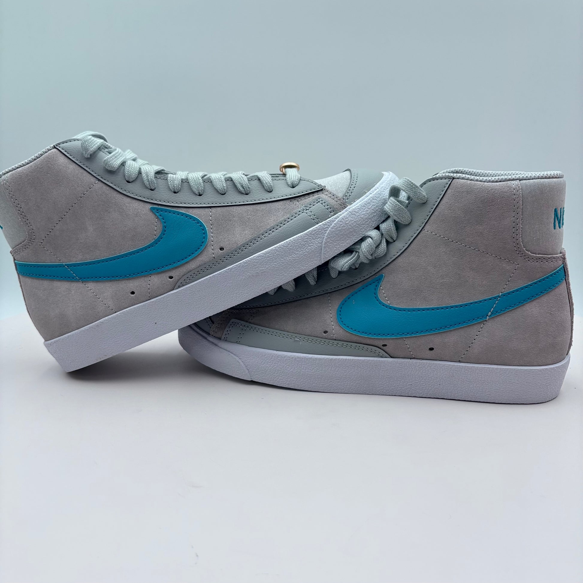 Gray sneakers with blue swoosh logo on a light gray background