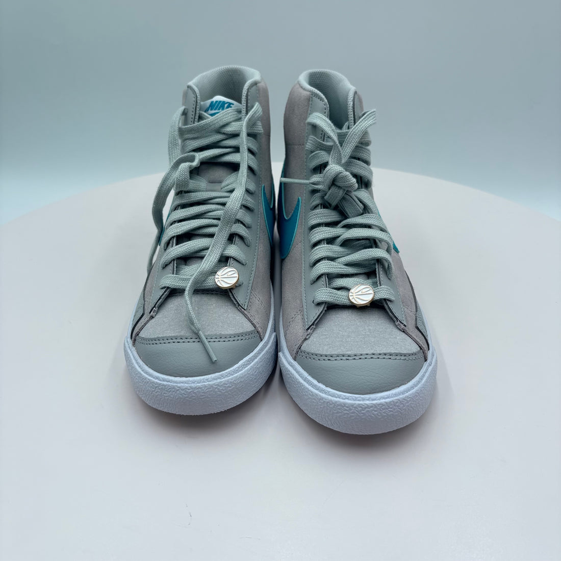 Pair of gray high-top sneakers with blue accents on a light gray background