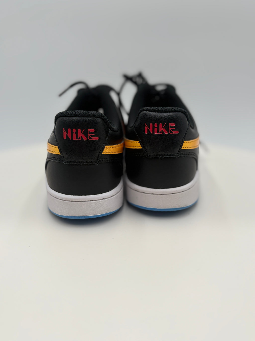 Black Nike sneakers with red and yellow accents on a white background
