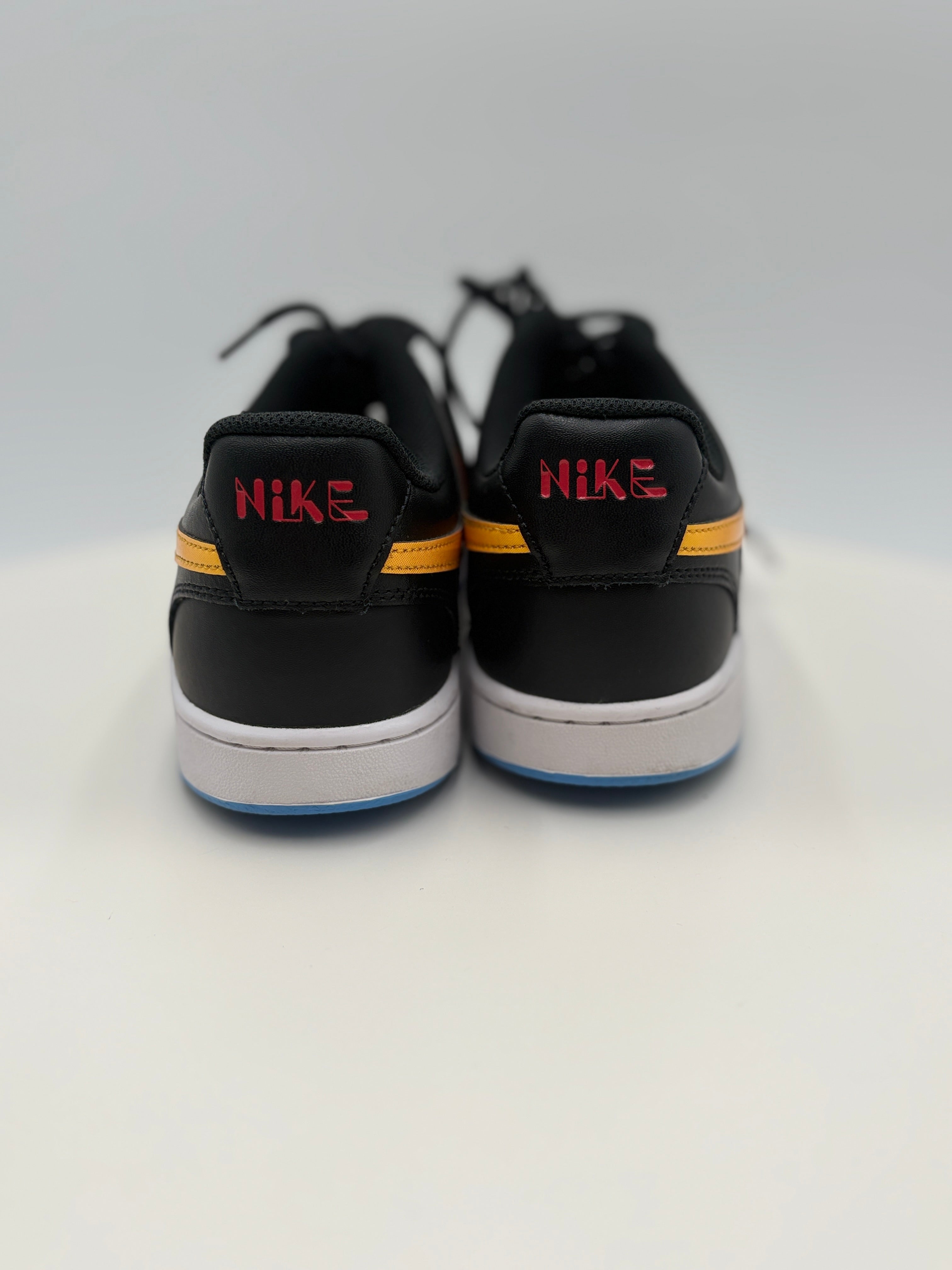 Black Nike sneakers with red and yellow accents on a white background