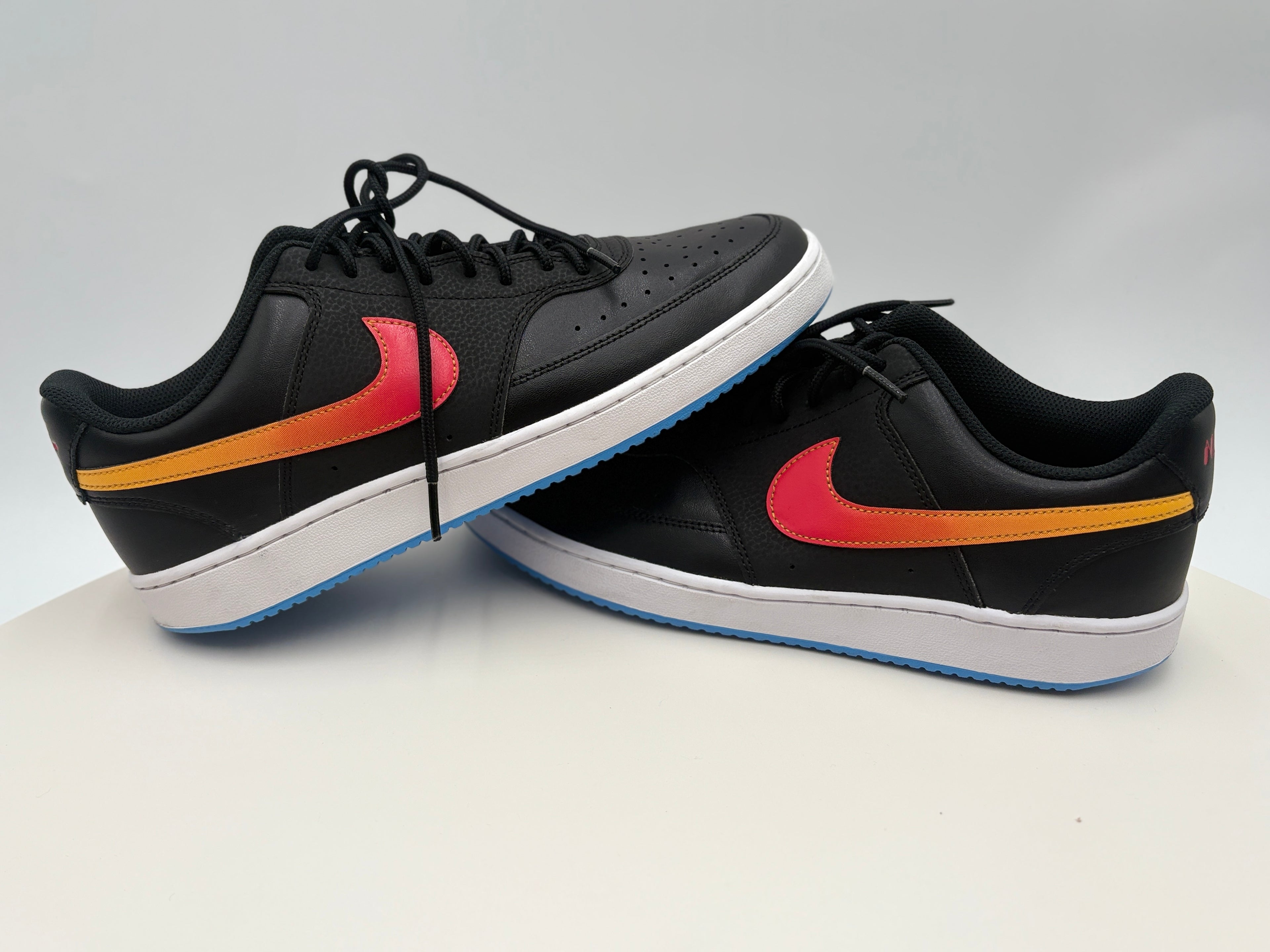 Black sneakers with a red and orange swoosh logo on a white background