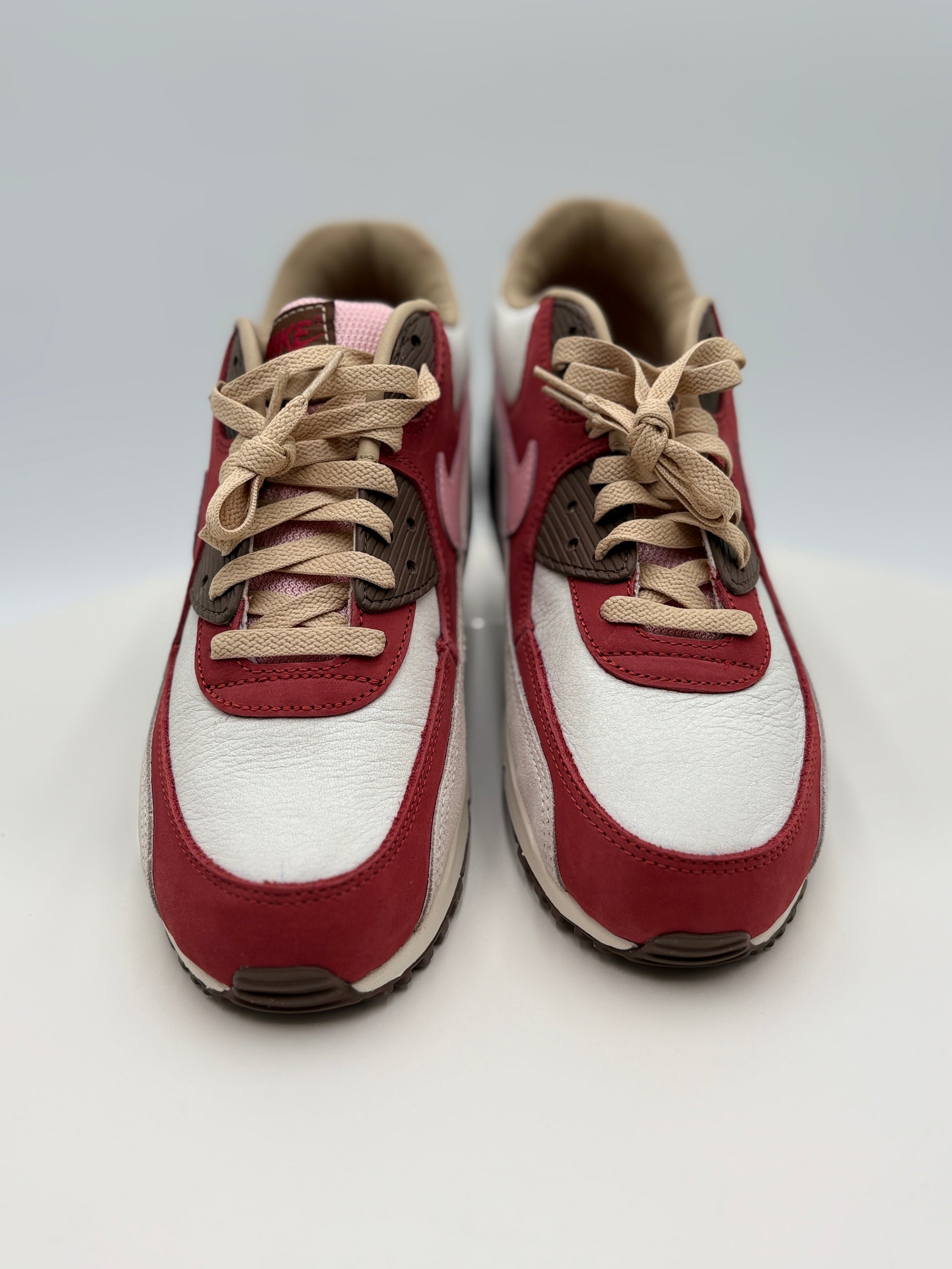 Pair of red and white sneakers with beige laces on a light gray background