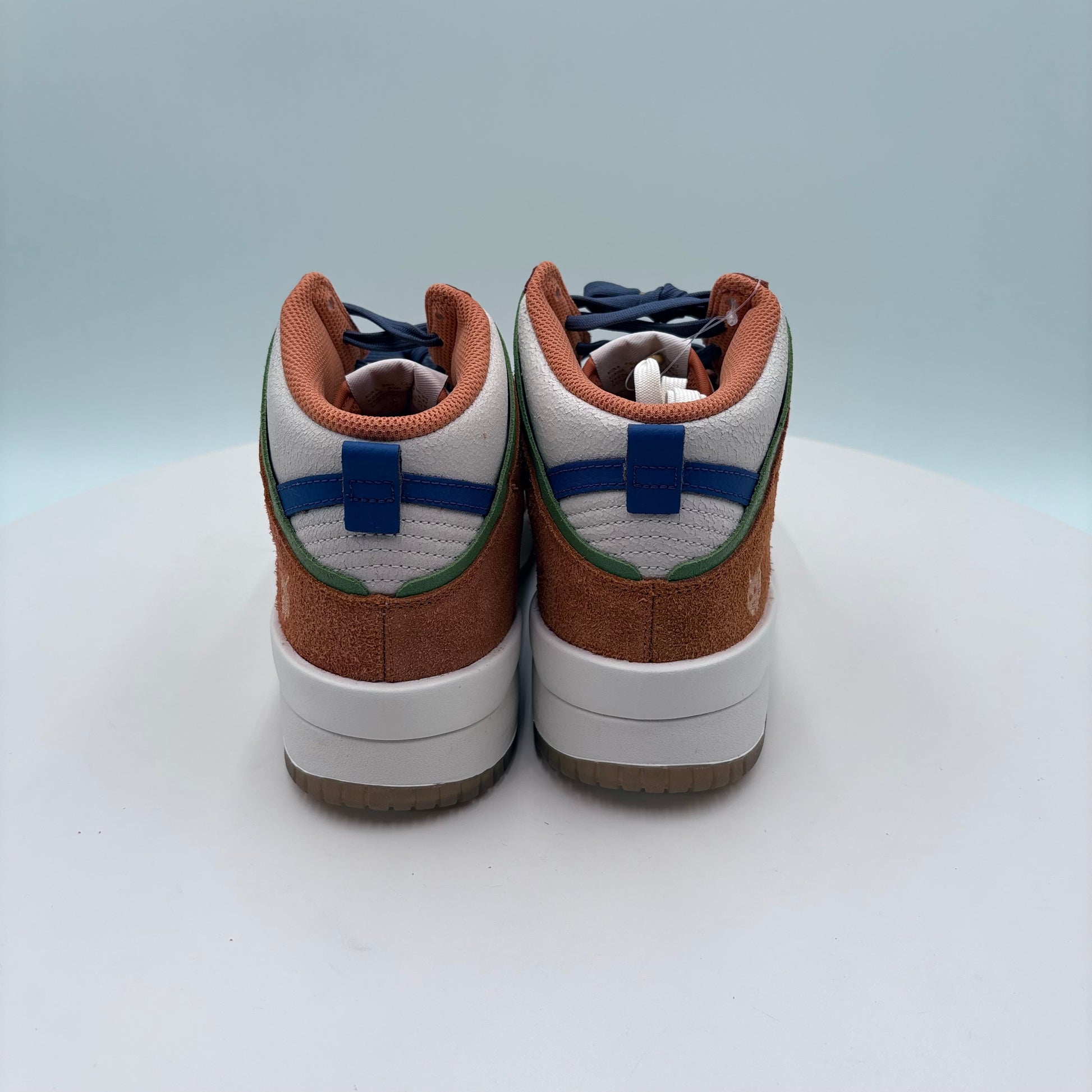 Pair of brown and white sneakers with blue accents on a light gray background