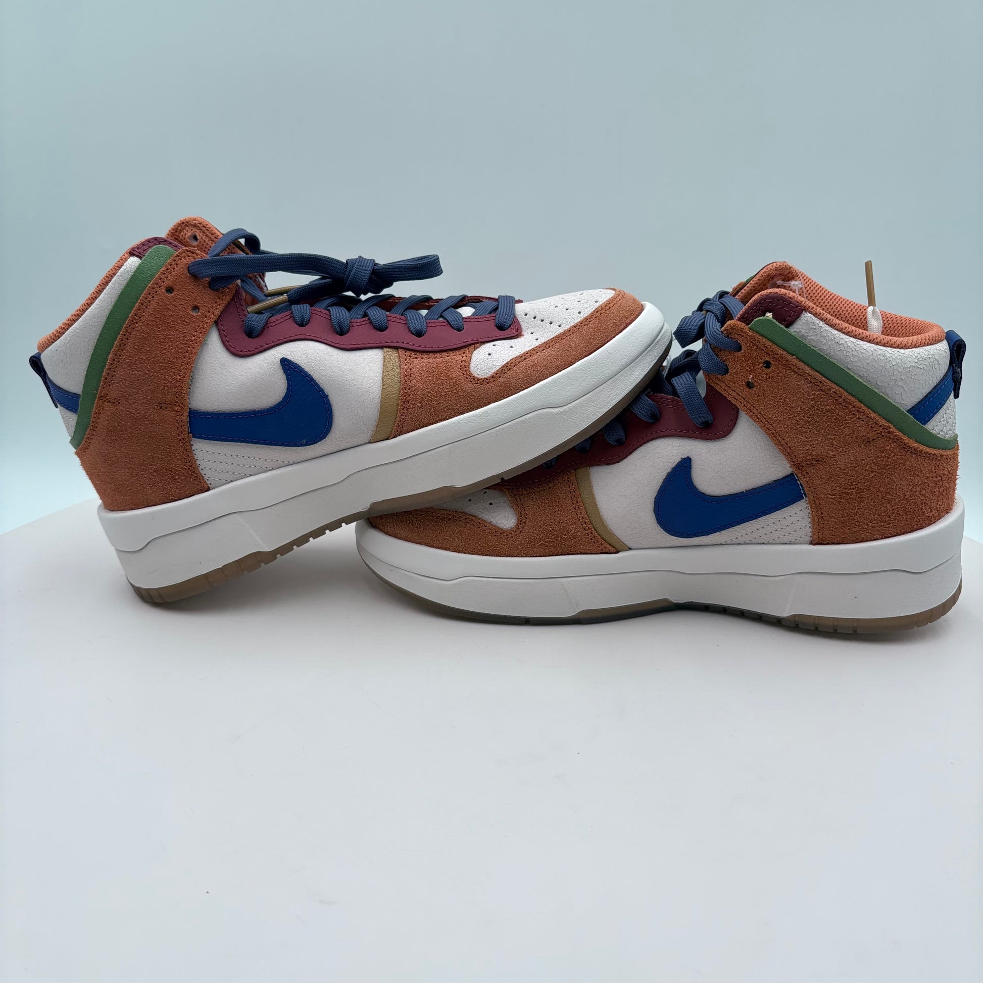 Pair of Nike sneakers with brown, blue, and white design on a light gray background
