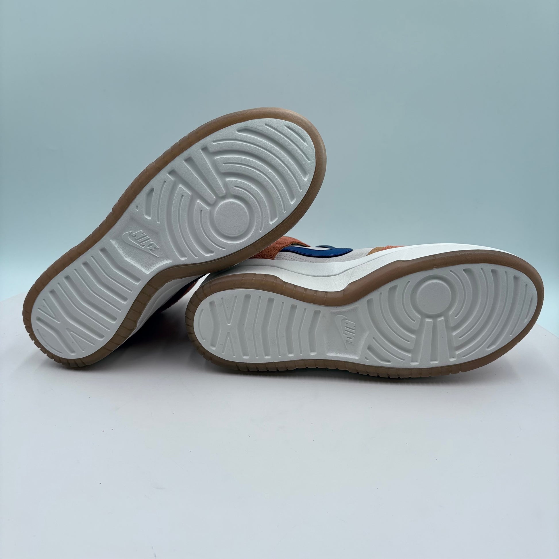 Close-up of a pair of sneakers with white soles and brown soles on a light gray background