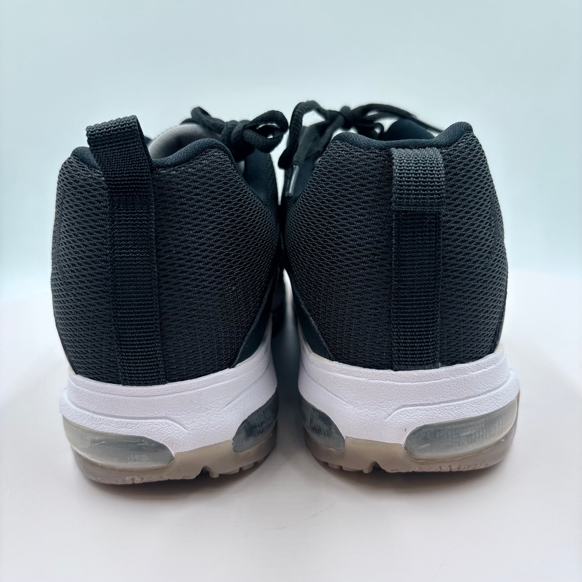 Black sneakers with white soles on a light gray background