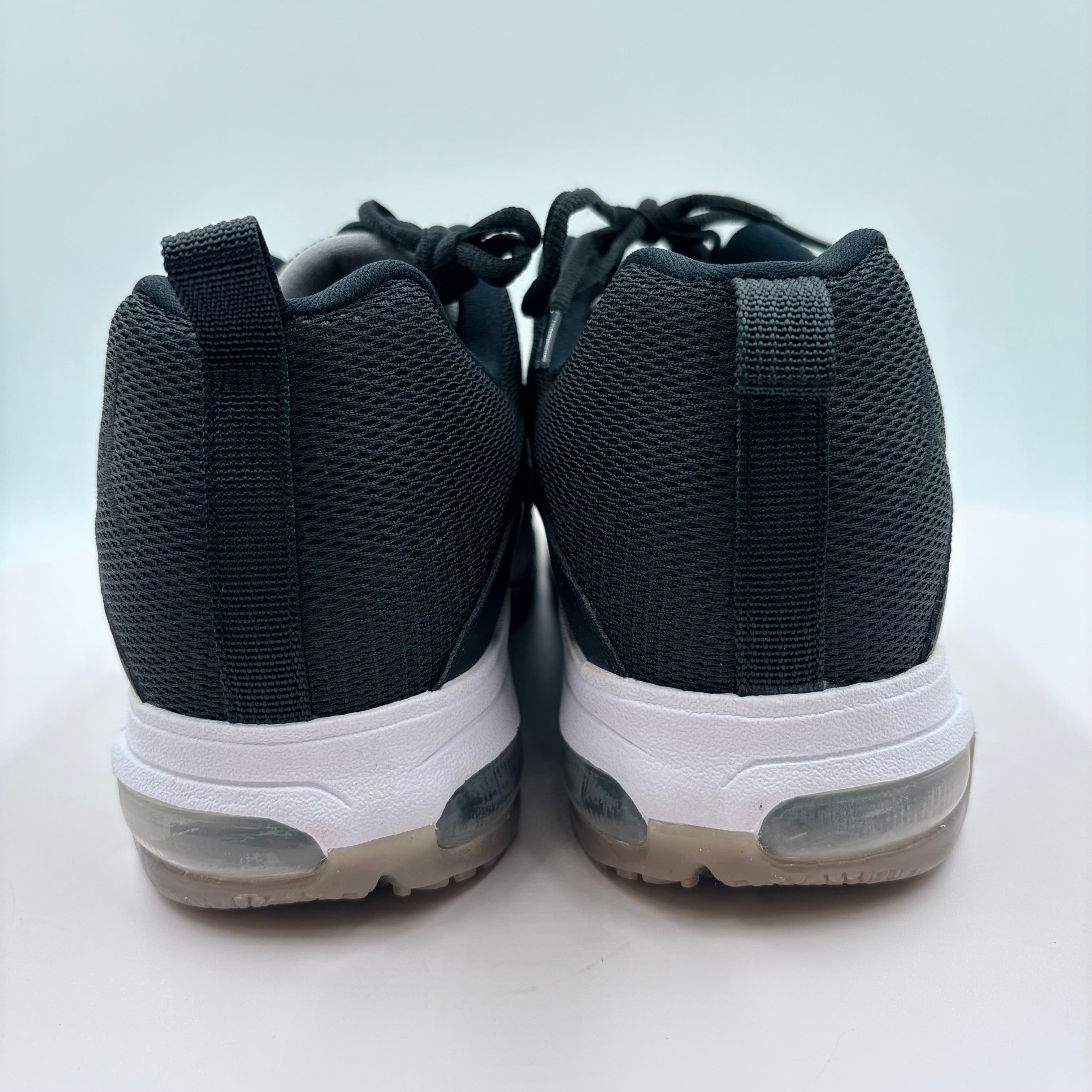Black sneakers with white soles on a light gray background