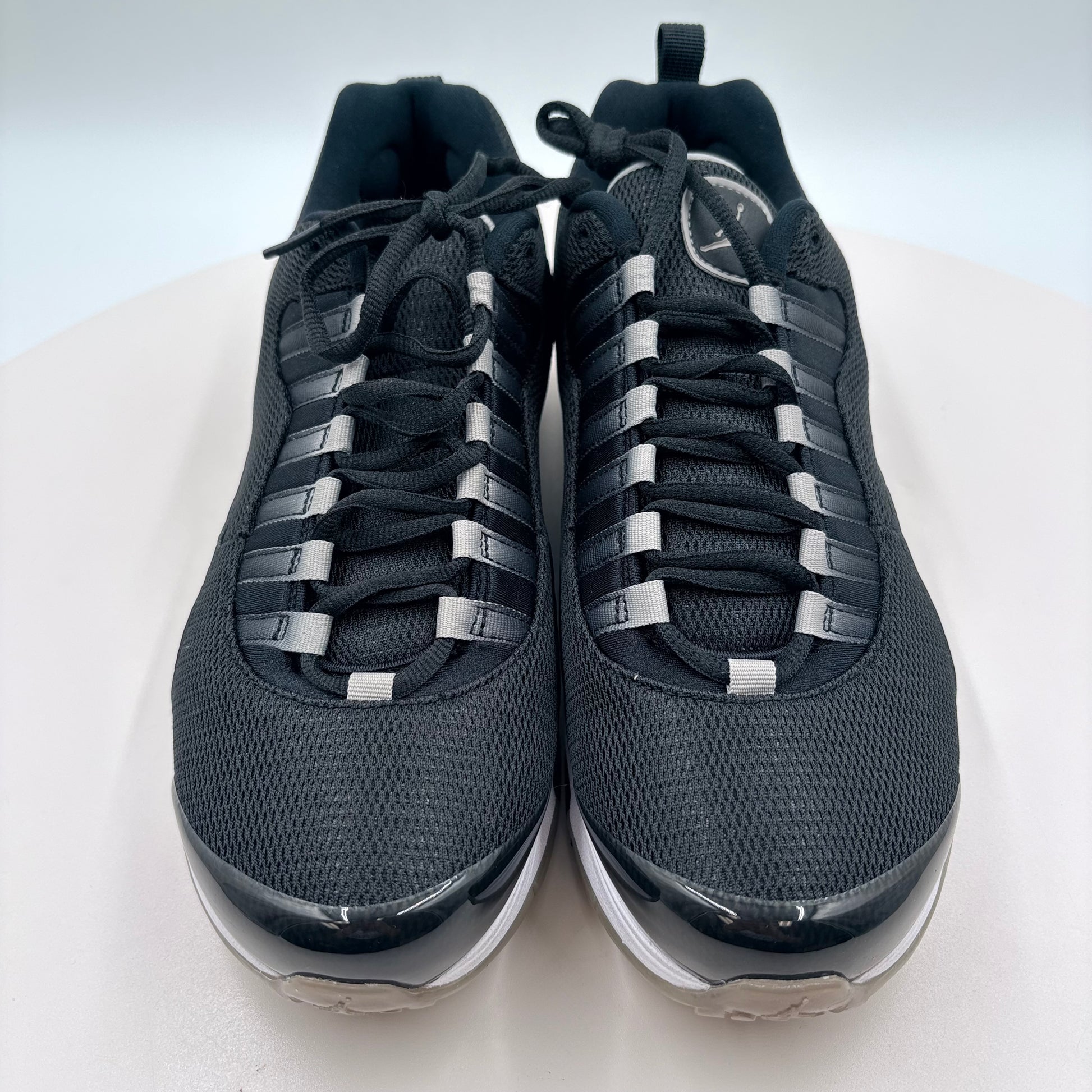 Pair of black athletic shoes with white soles on a light gray background