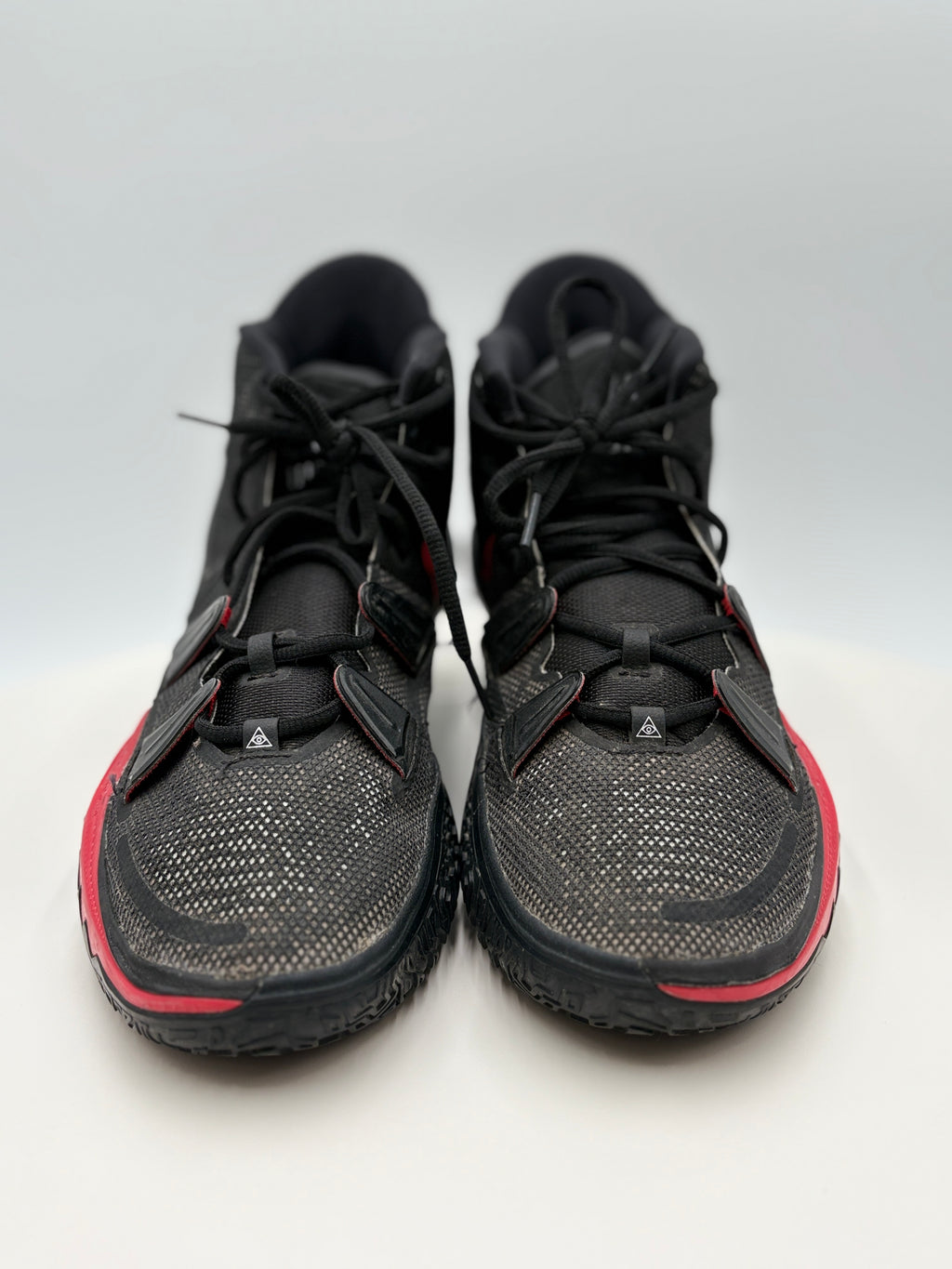 Front - Black athletic shoes with red accents on a light gray background