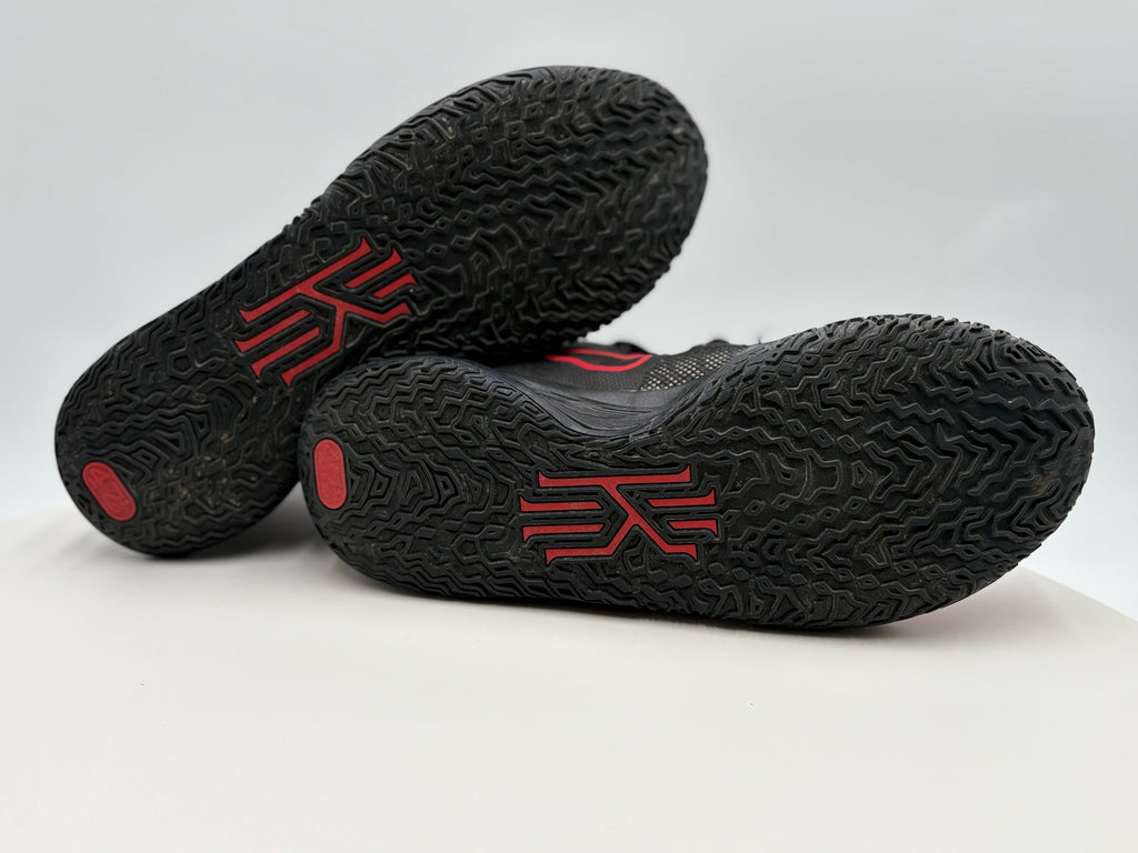 Sole of Black athletic shoes with red accents on a white background