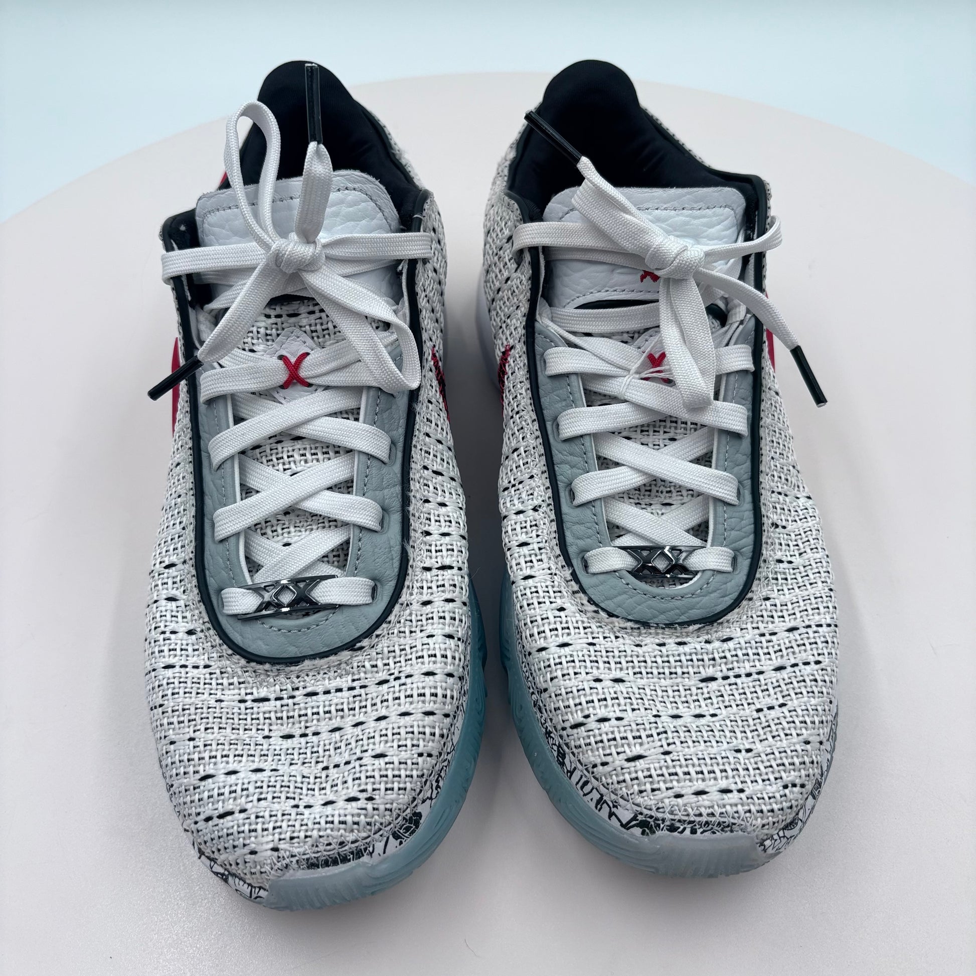 Pair of gray and black sneakers with white laces on a light blue background