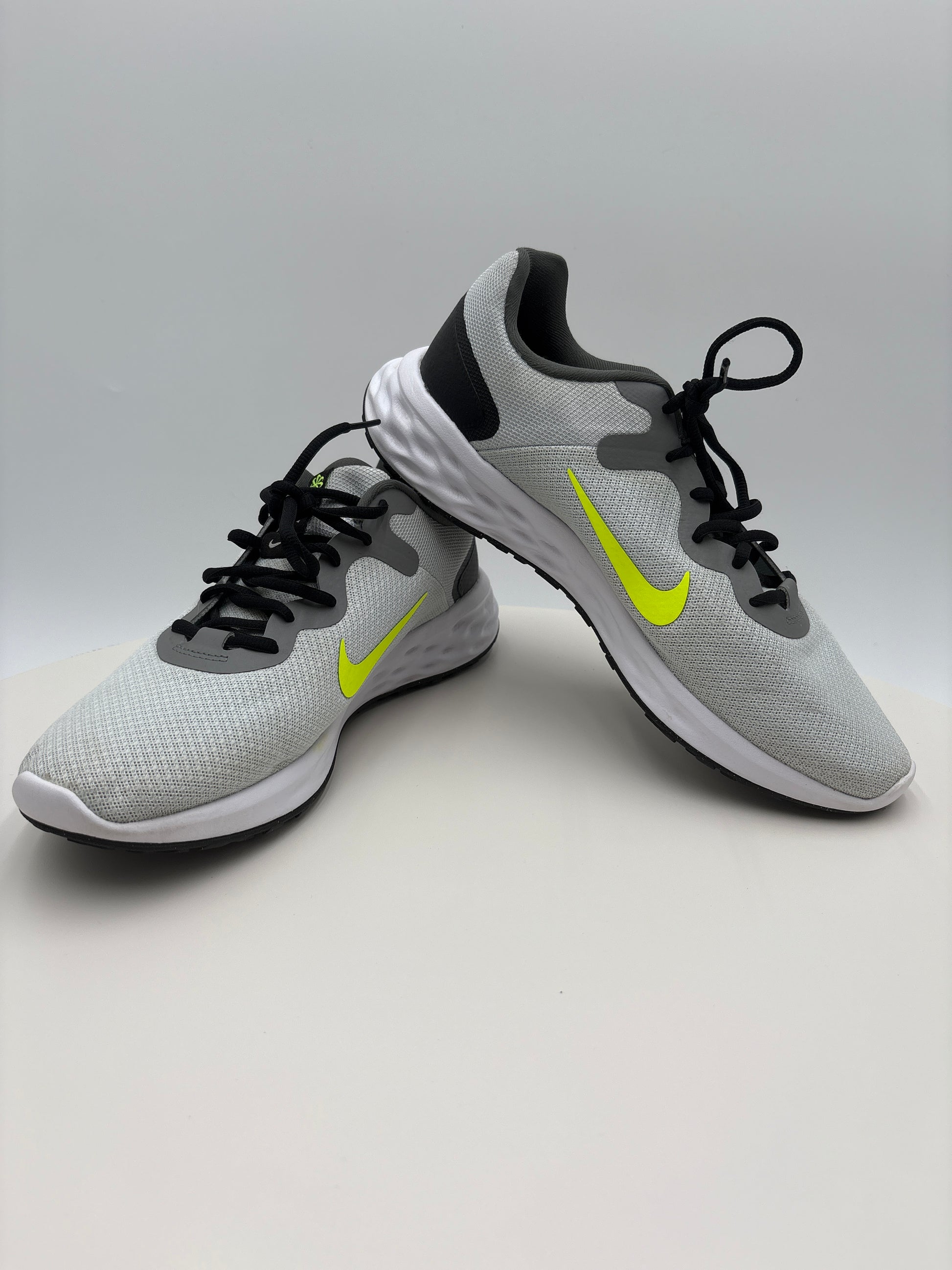 Gray running shoes with black and yellow accents on a light gray background