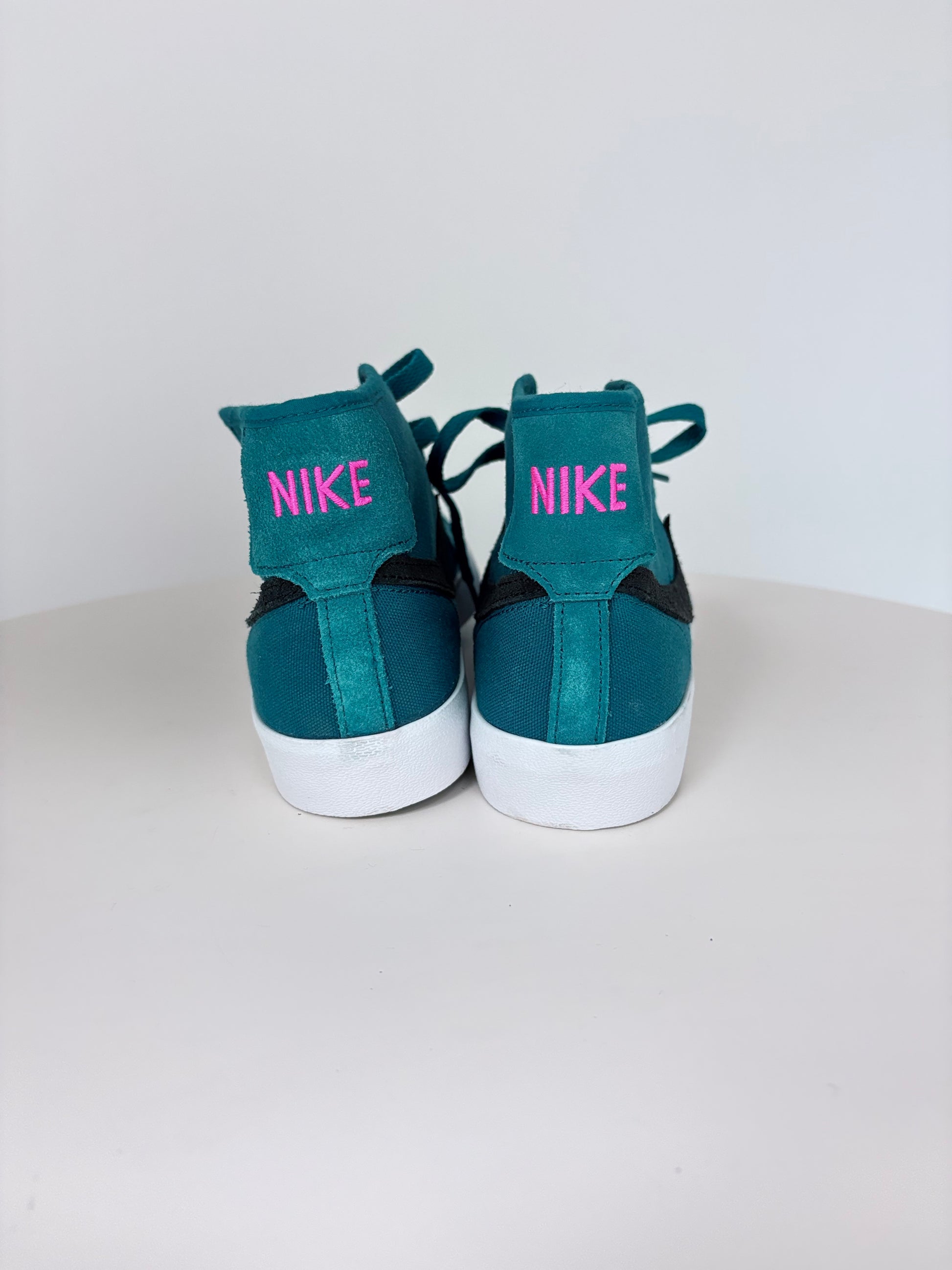 Teal Nike sneakers with pink text on a white background