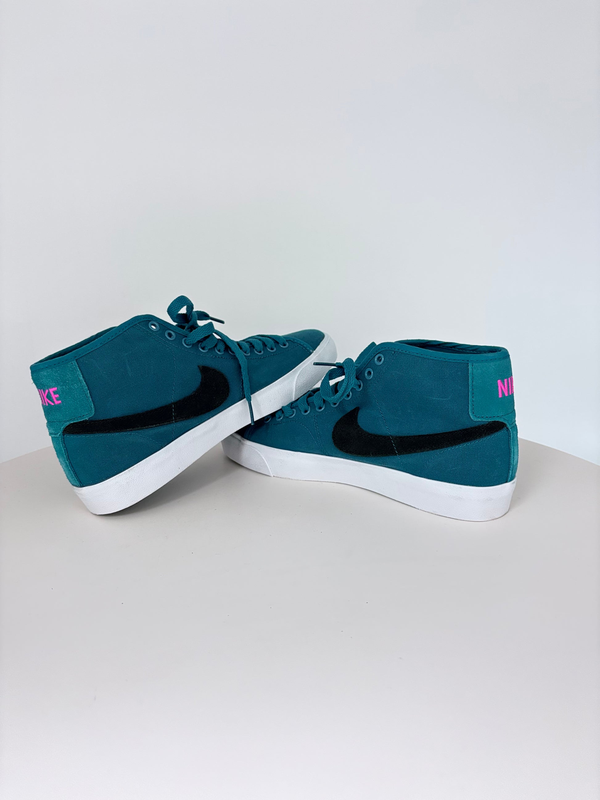 Pair of teal sneakers with white soles on a light gray background