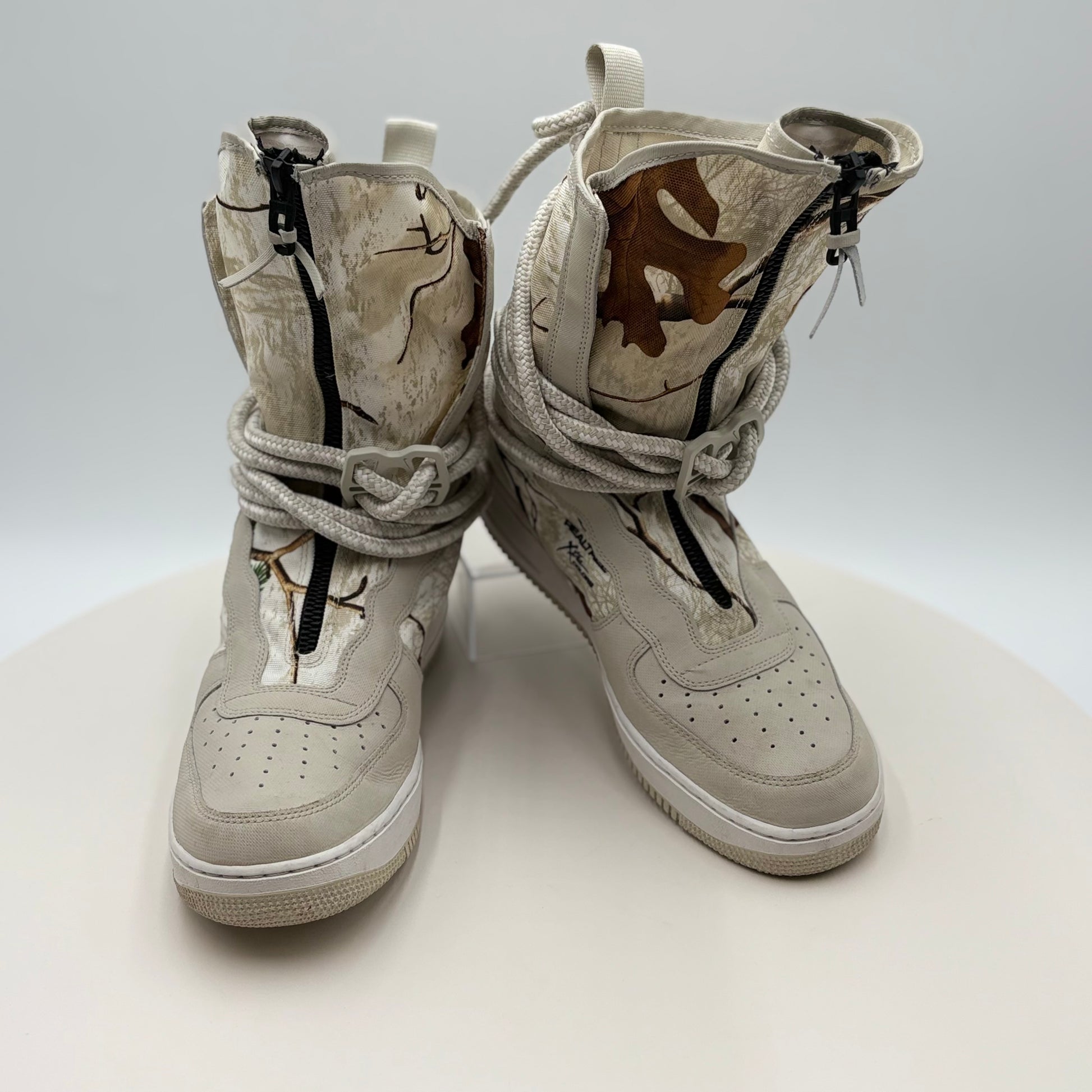 Pair of beige high-top sneakers with camouflage patterns on a white background