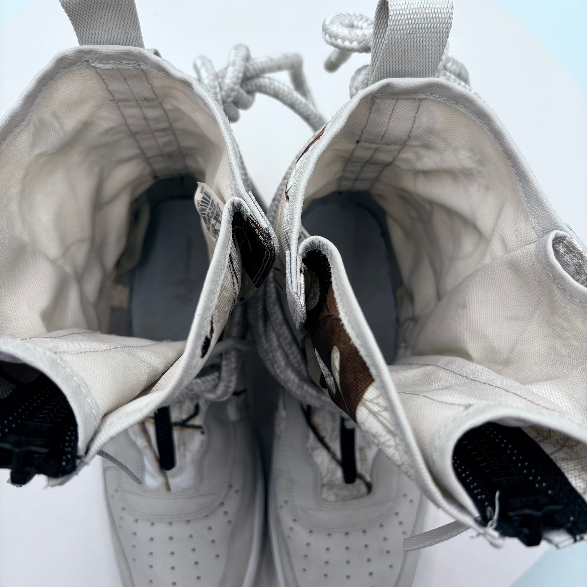 Close-up of a pair of white sneakers with visible wear and tear on a light blue background