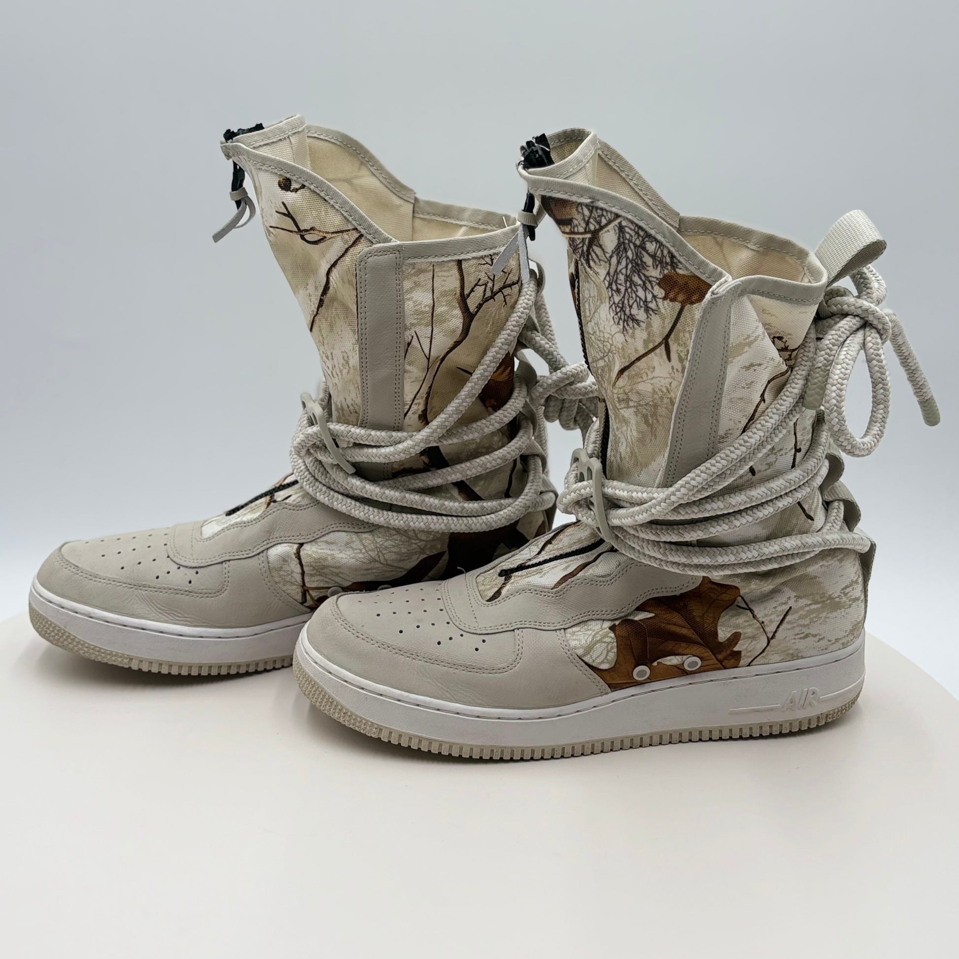 Pair of camouflage-patterned high-top sneakers on a light gray background
