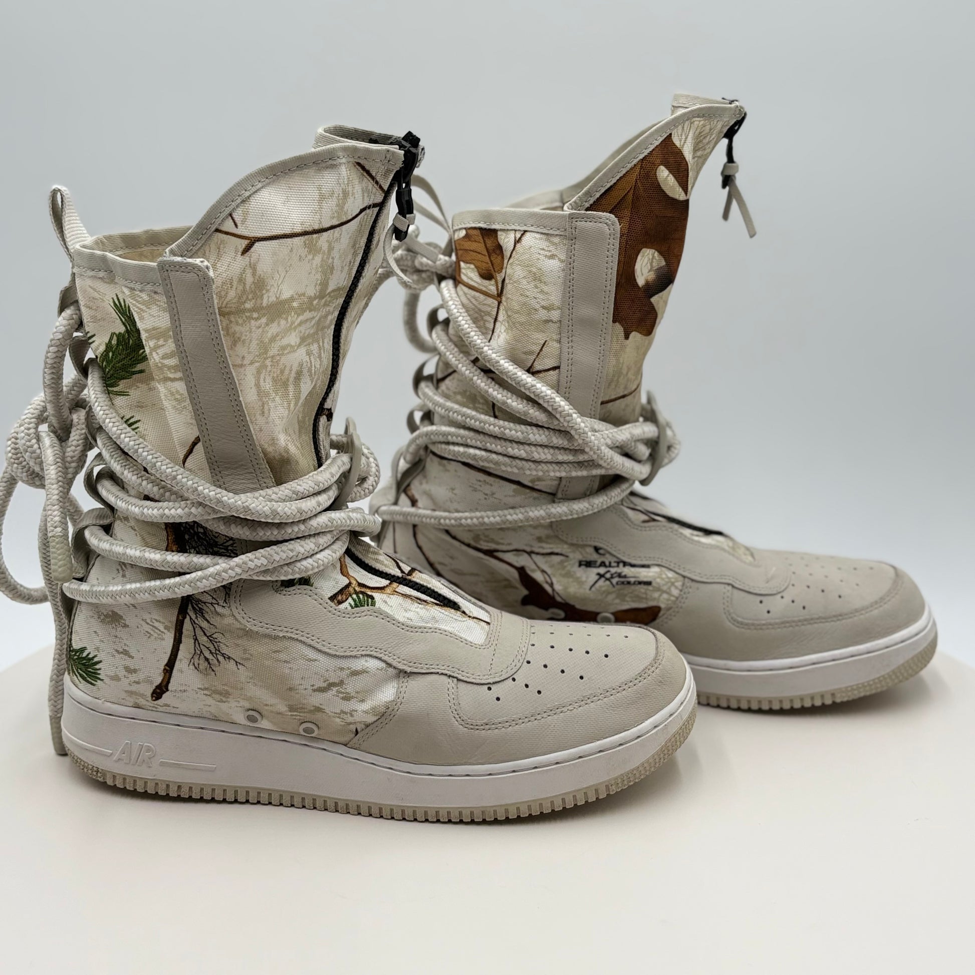 Pair of beige camouflage sneakers with tied laces on a light gray background