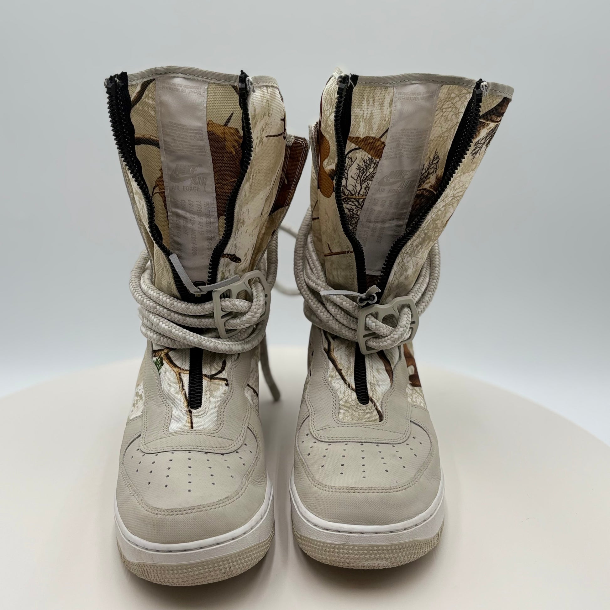 Pair of beige high-top sneakers with zippers on a white background