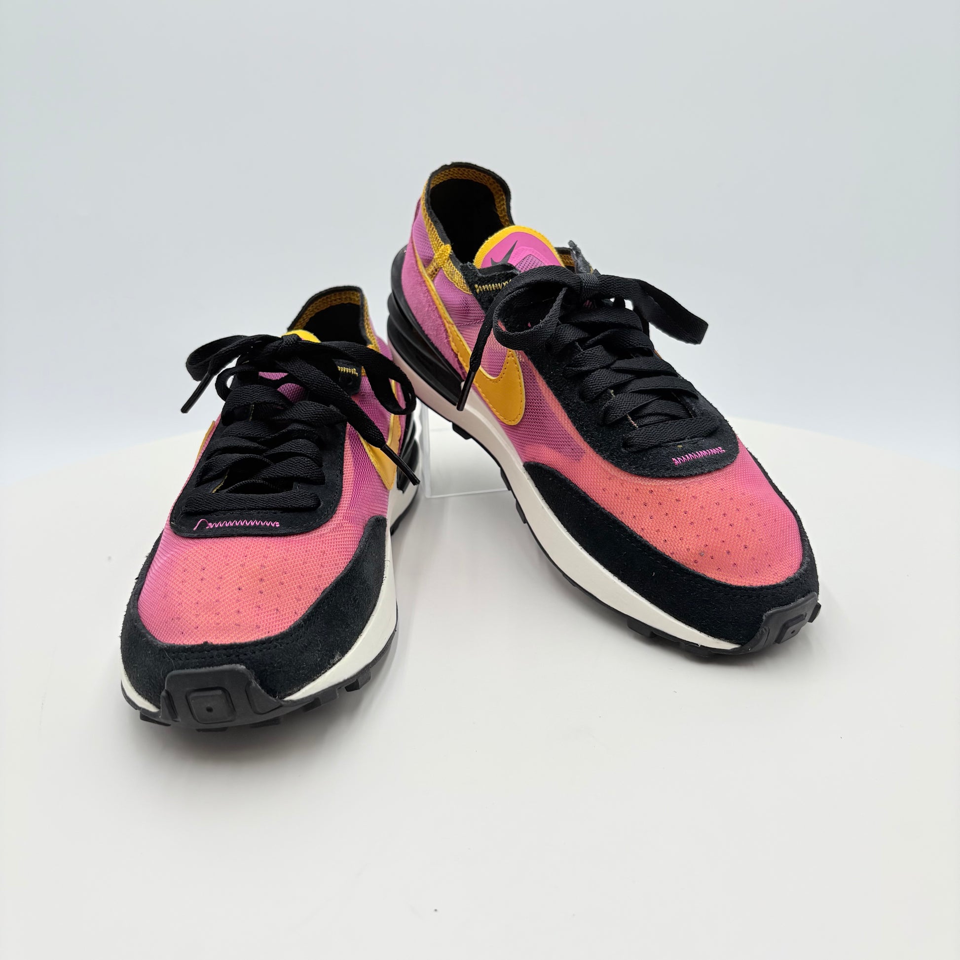 Pair of pink and black sneakers with yellow accents on a white background
