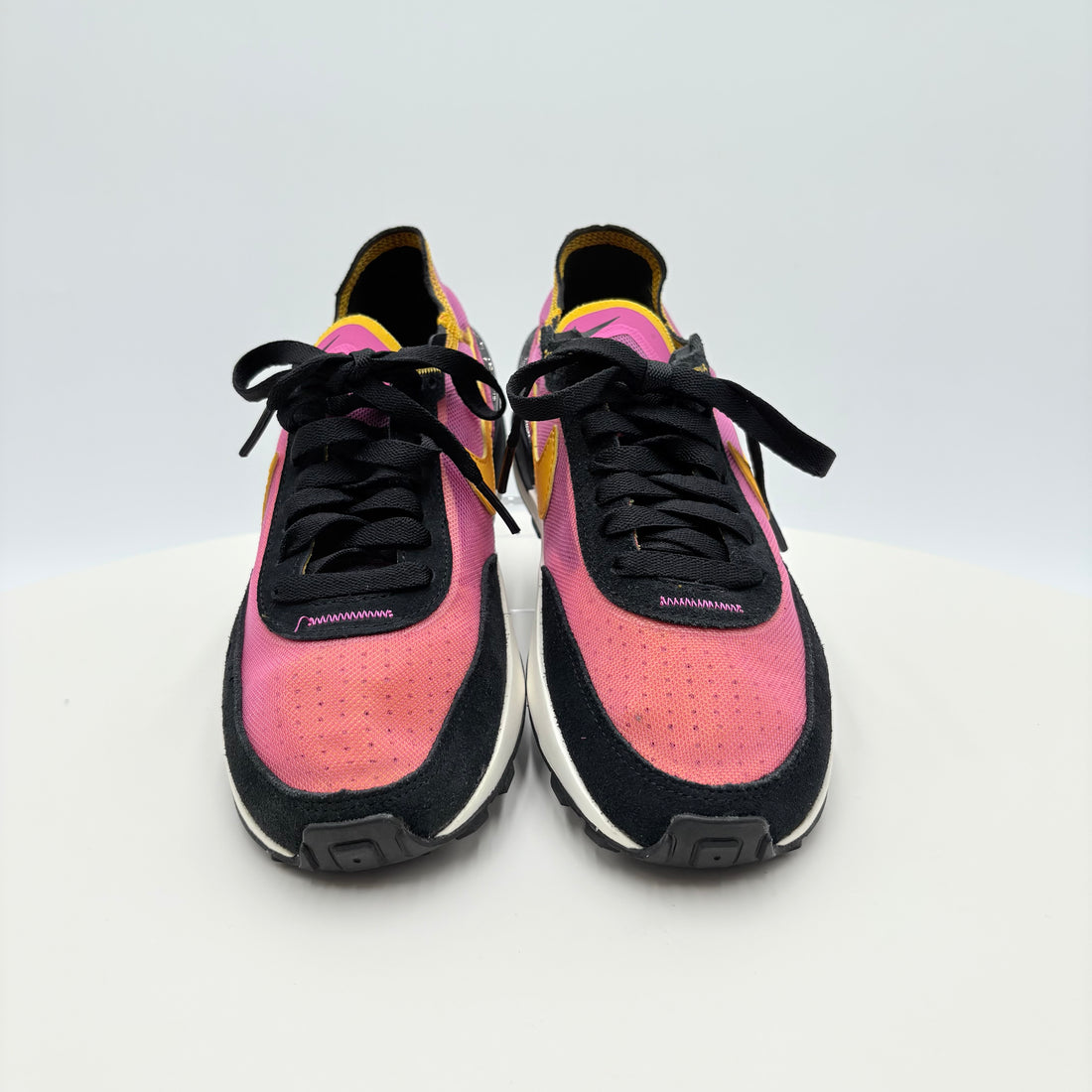 Pair of pink and black sneakers with yellow accents on a white background